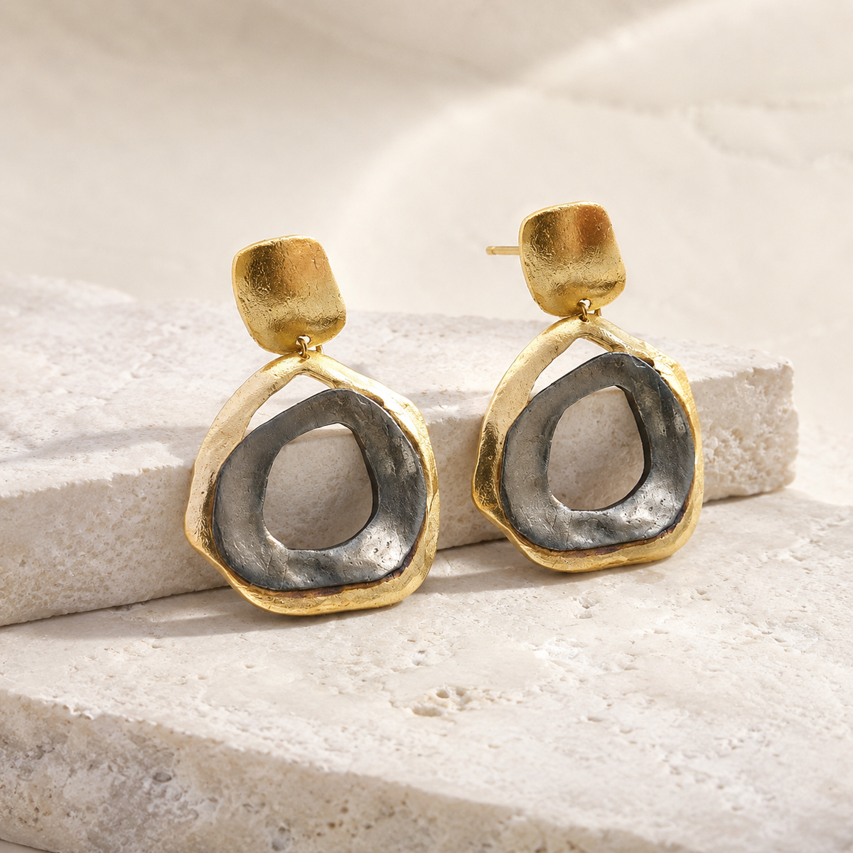Angle view of abstract circle drop earrings with a two-tone finish.