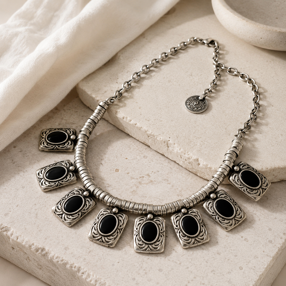 Angled view of a silver-tone necklace with black rectangular charms.