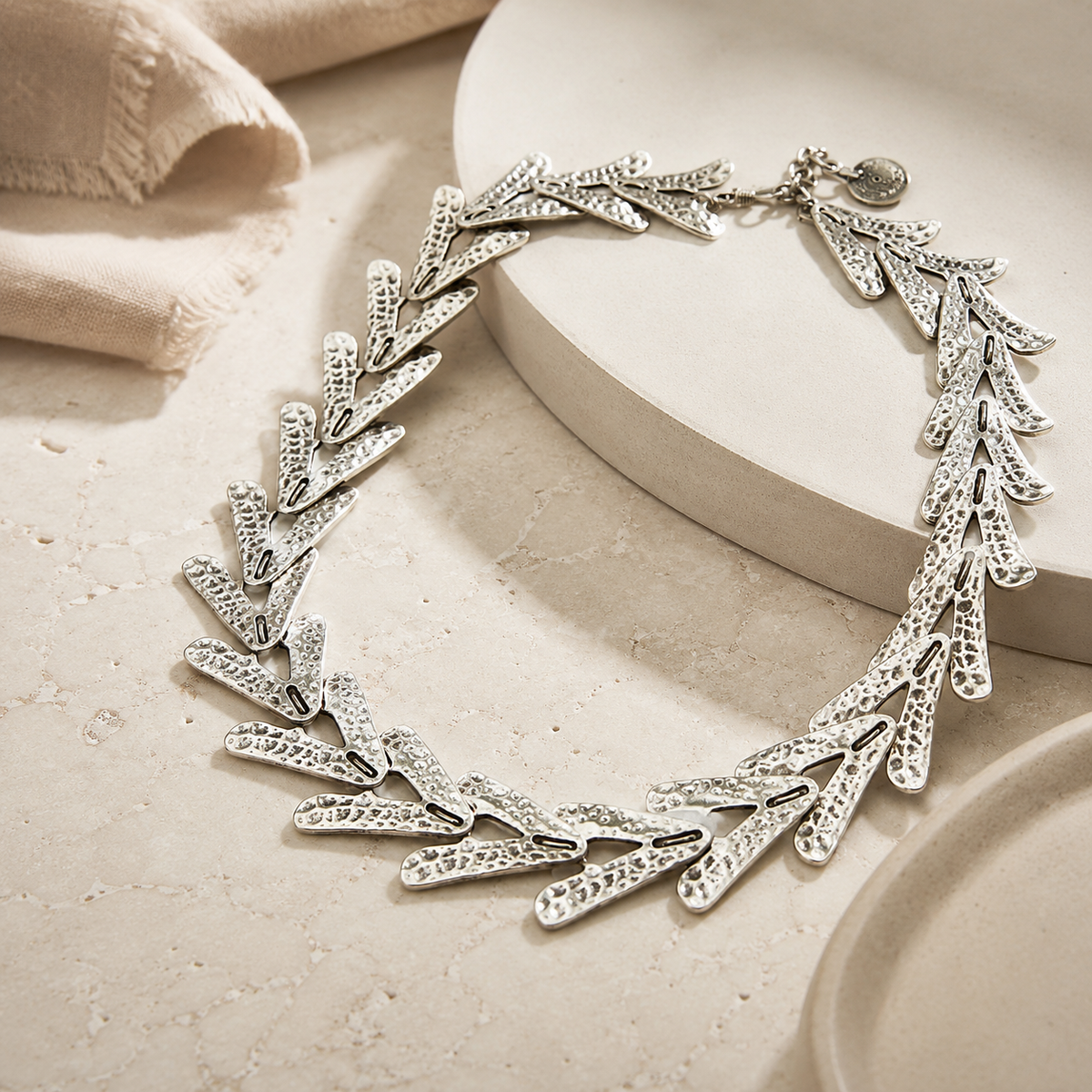 Angled view of a textured silver-tone arrow link necklace.