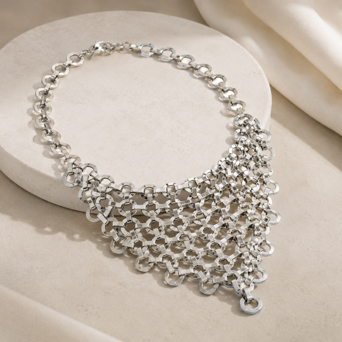 Angled view of a silver-tone mesh bib statement necklace.