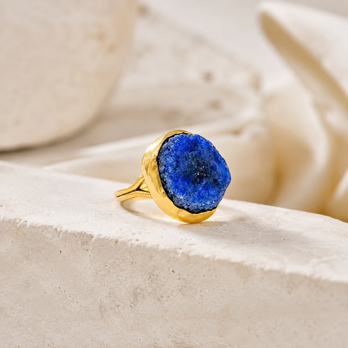 Angle view of a gold-plated statement ring with raw lapis lazuli.
