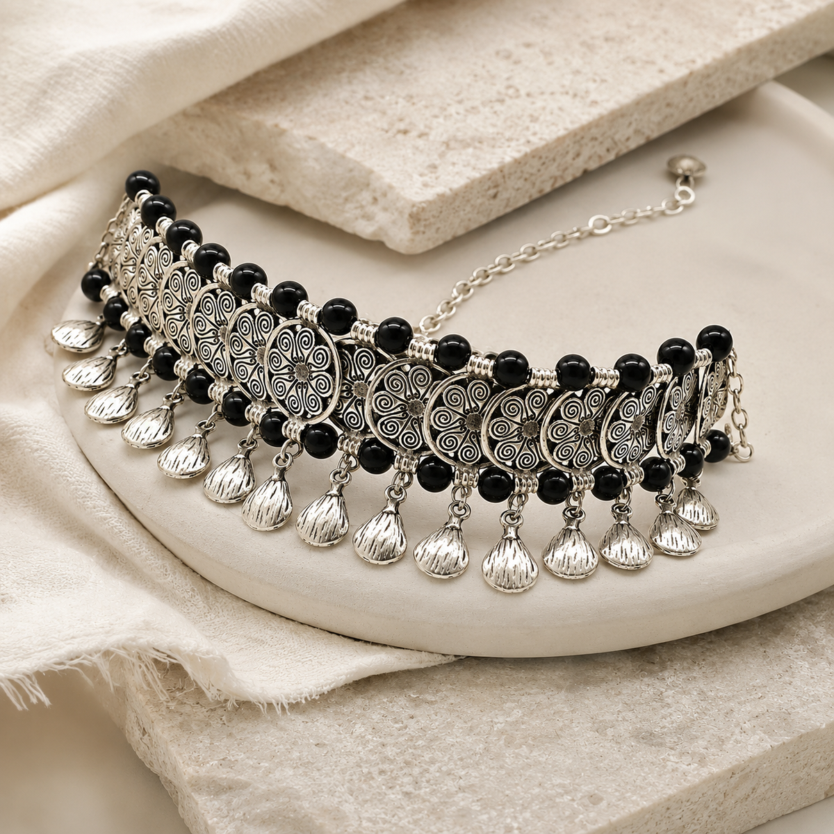 Angled view of a black bead choker necklace with filigree coin charms.