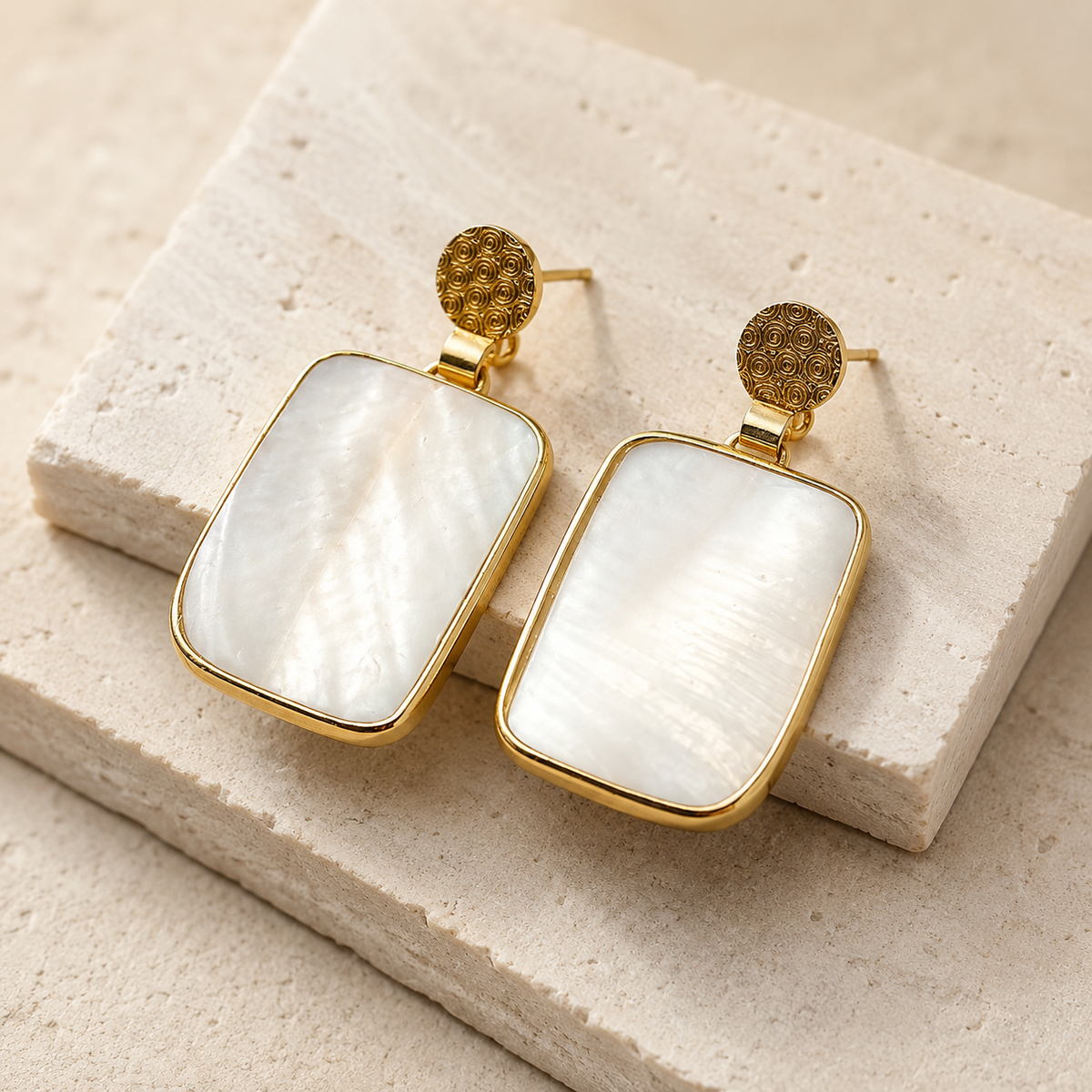 Angle view of rectangular clear quartz earrings with gold plated edges.