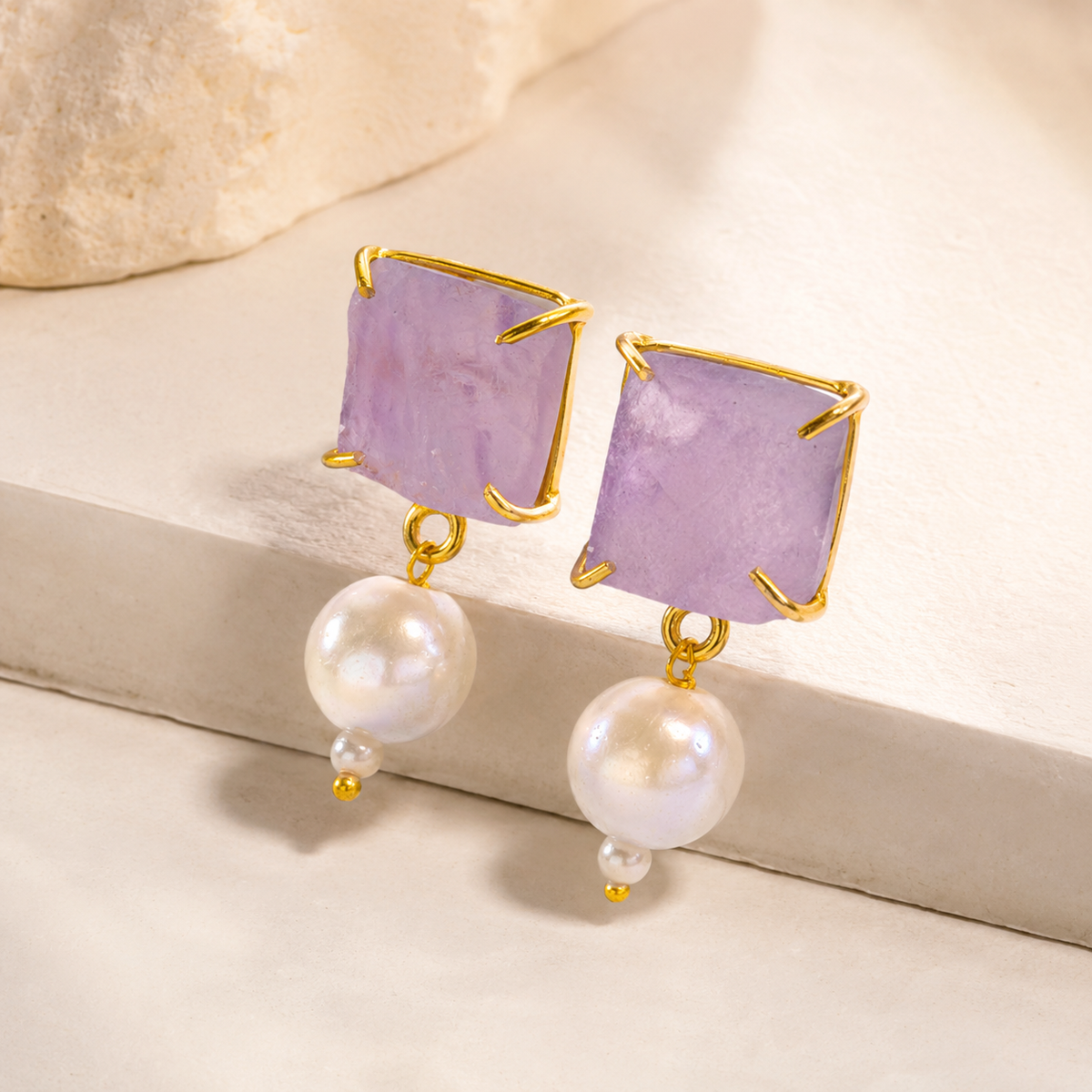 Angle view of rough amethyst-style drop earrings with pearl accents.