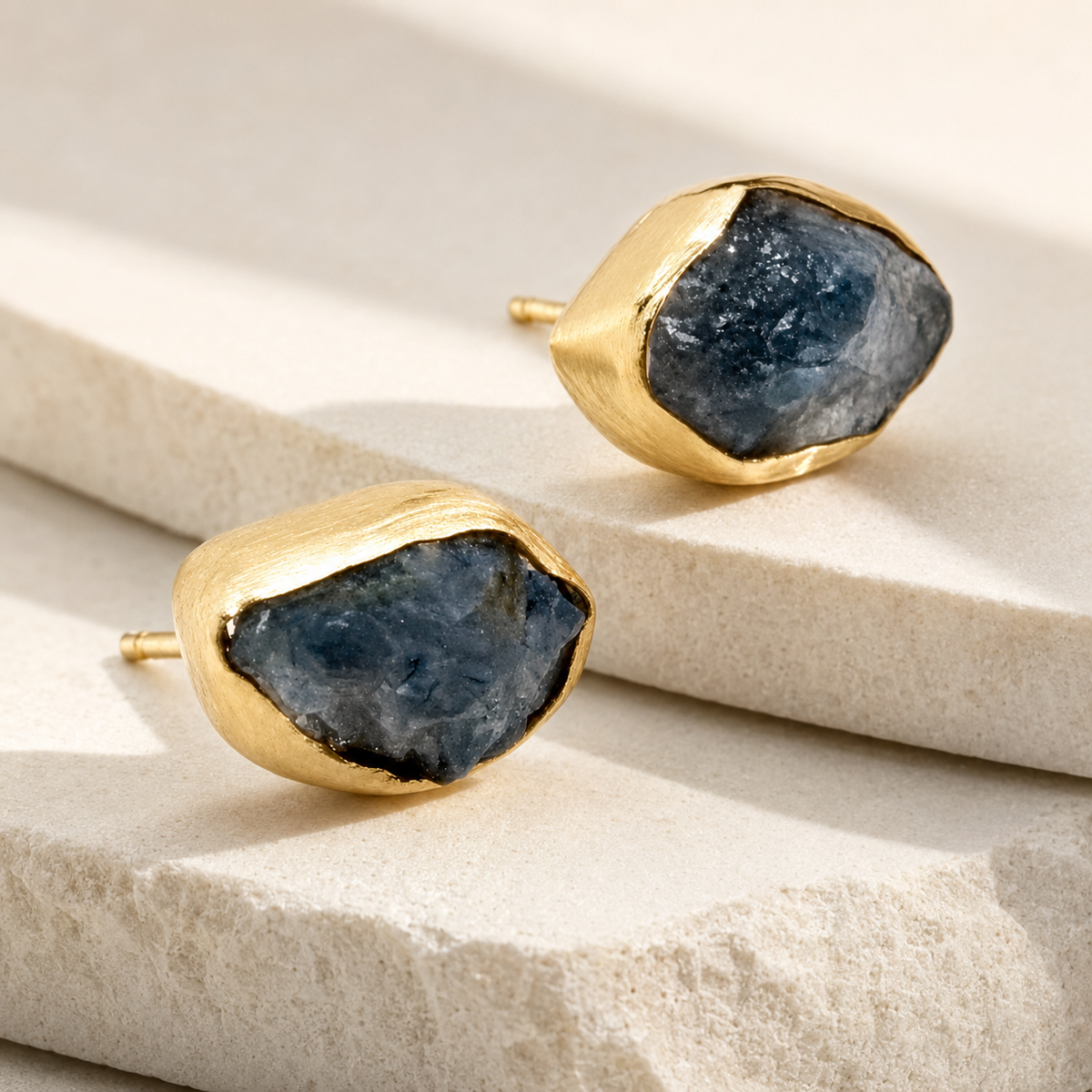 Angled view of heart stud earrings with a gold-plated setting and red crystal center.