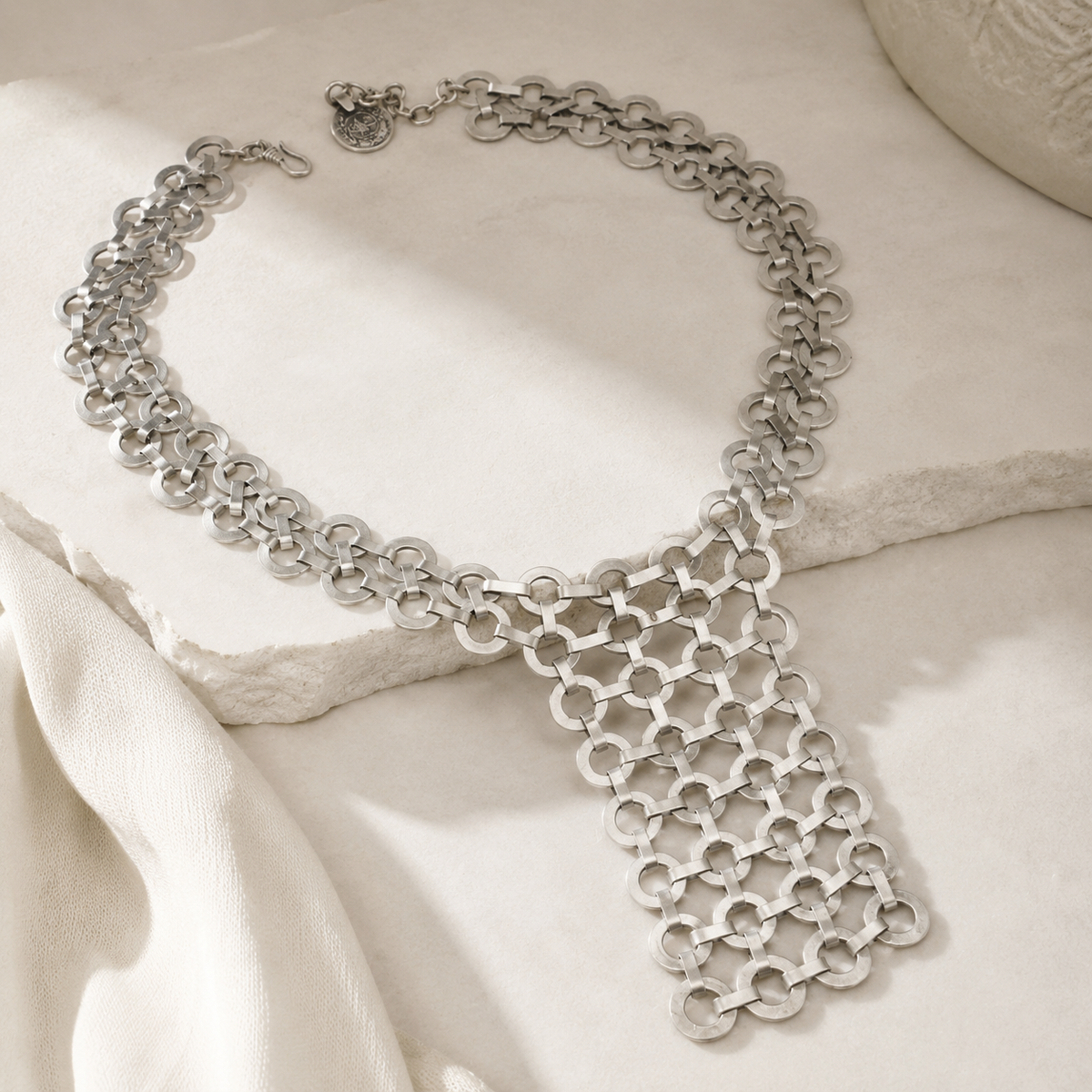 Angled view of a silver link bib statement necklace.