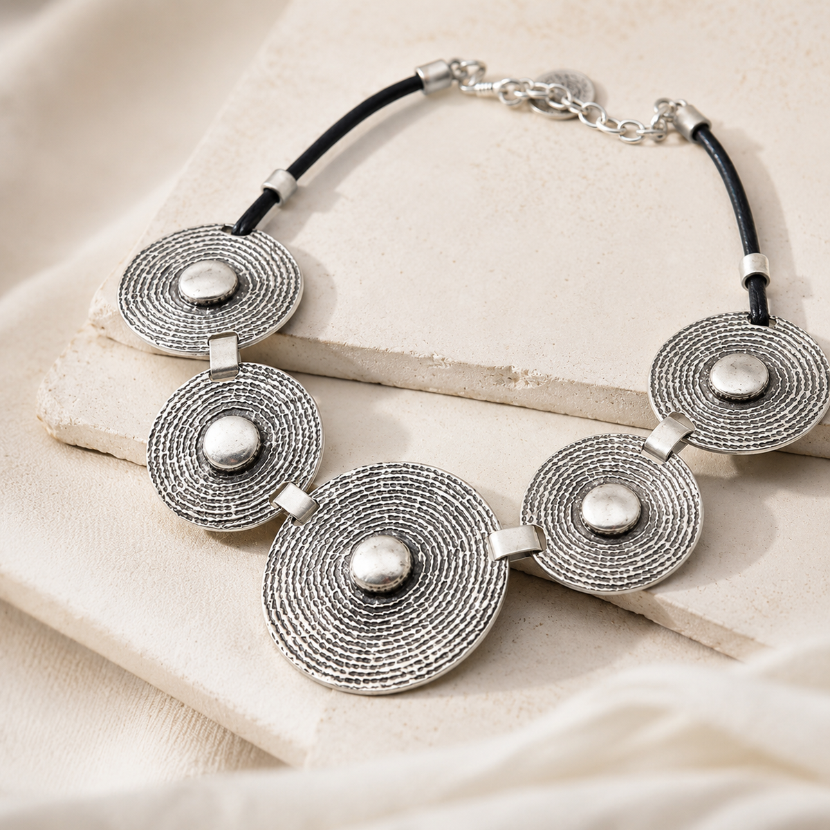Angled view of a concentric disc statement necklace with textured silver-tone discs.