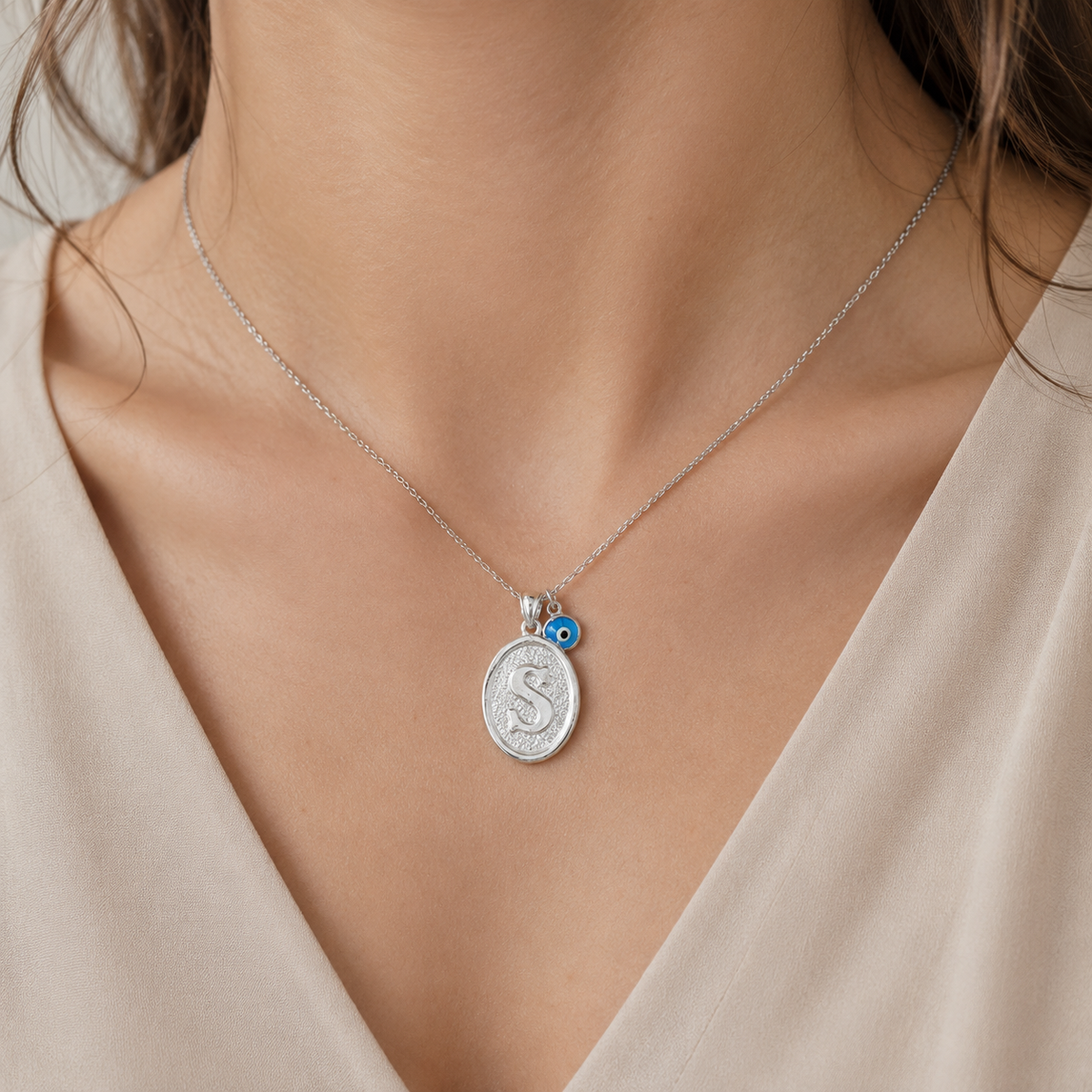 Angled view of a personalized initial necklace with a silver-tone chain and oval pendant.