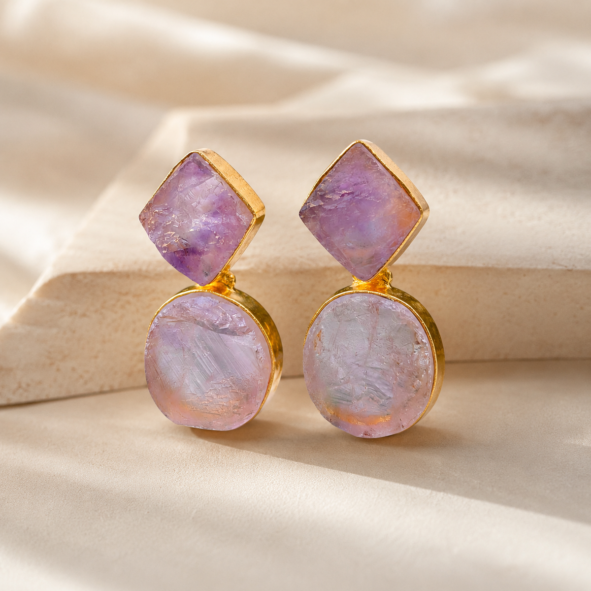 Angled view of gold-plated rough amethyst drop earrings with a textured stone surface.