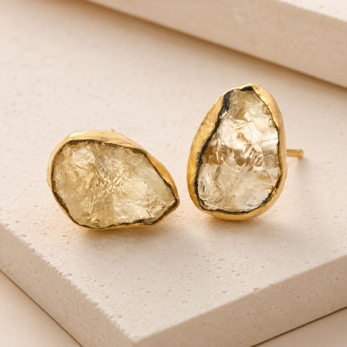 Angle view of raw quartz stud earrings in a gold-plated setting.