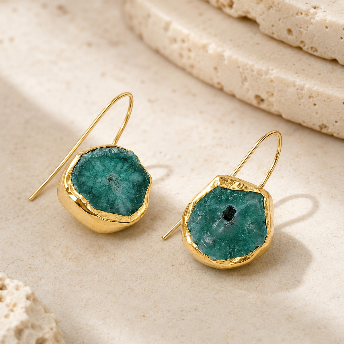 Angle view of gold-plated drop earrings with brown druzy mother of pearl centers.