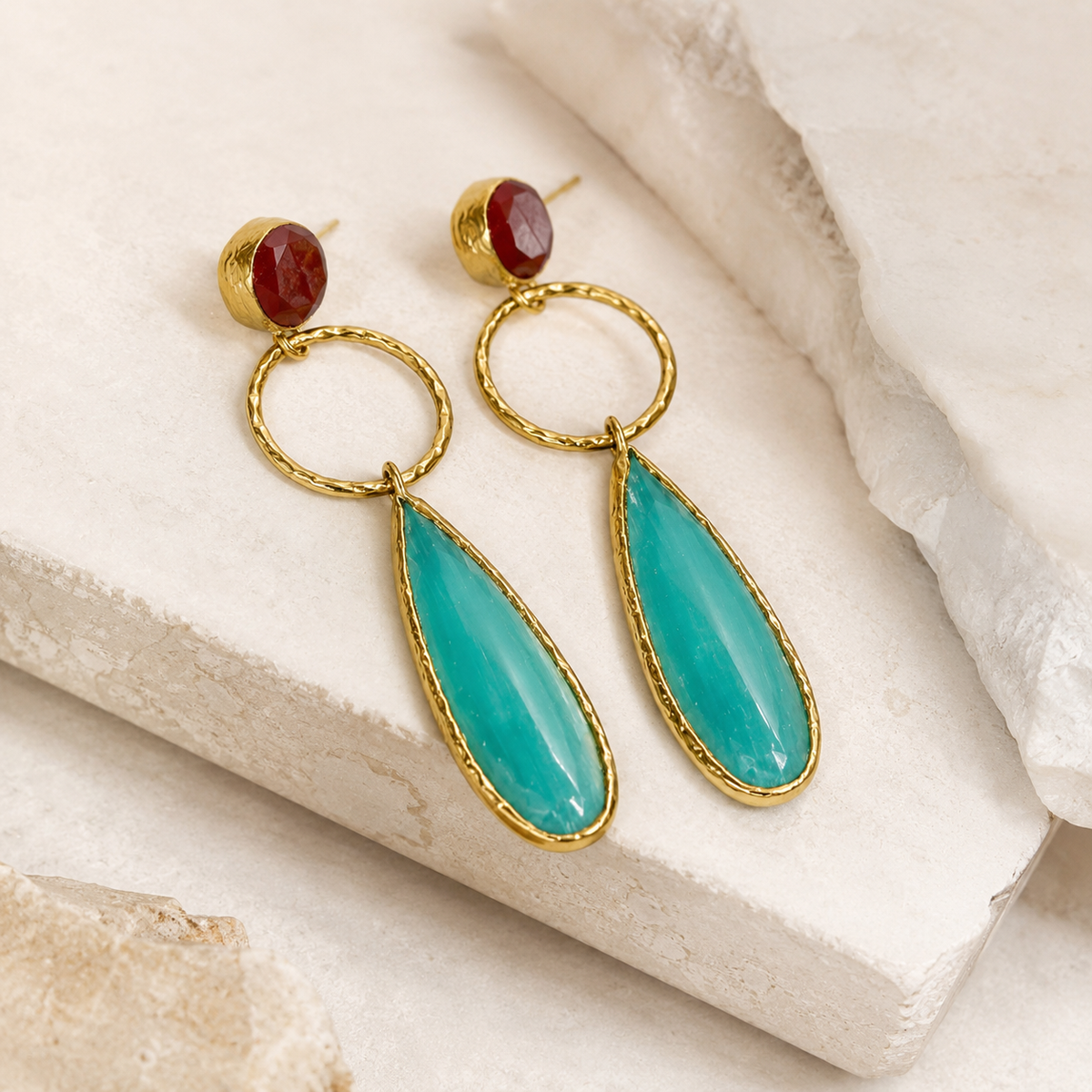 Gold-plated drop earrings shown at an angle with textured circular links, pine green leaf-shaped pendants, and a small red stone top.