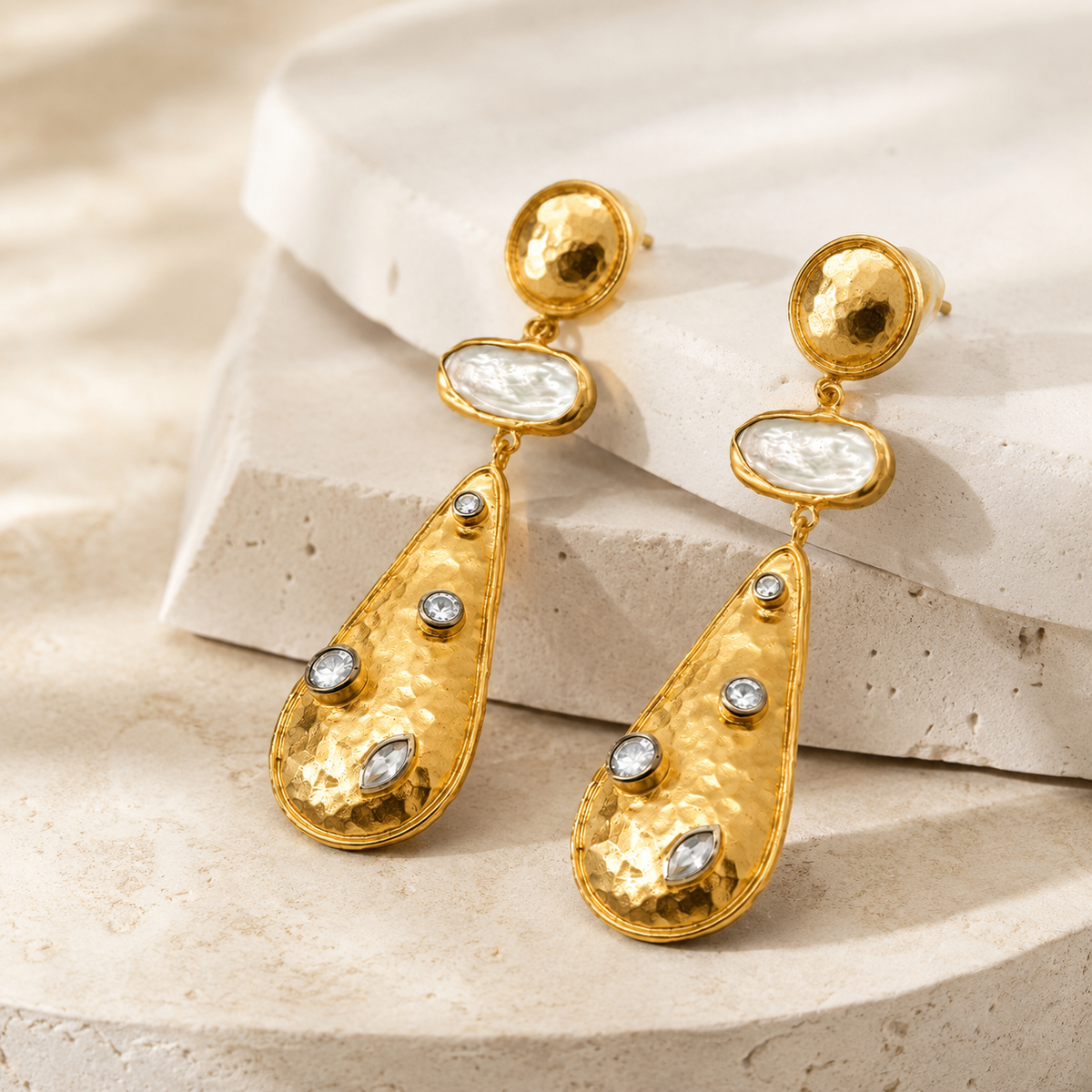 Angle view of gold-plated drop earrings with a sculptural silhouette.