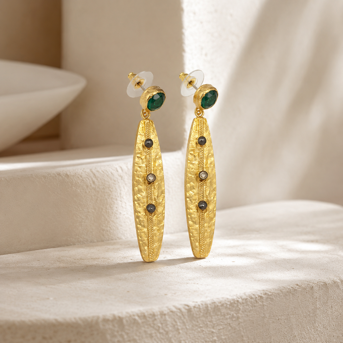 Angled view of olive green stone and gold-plated drop earrings.