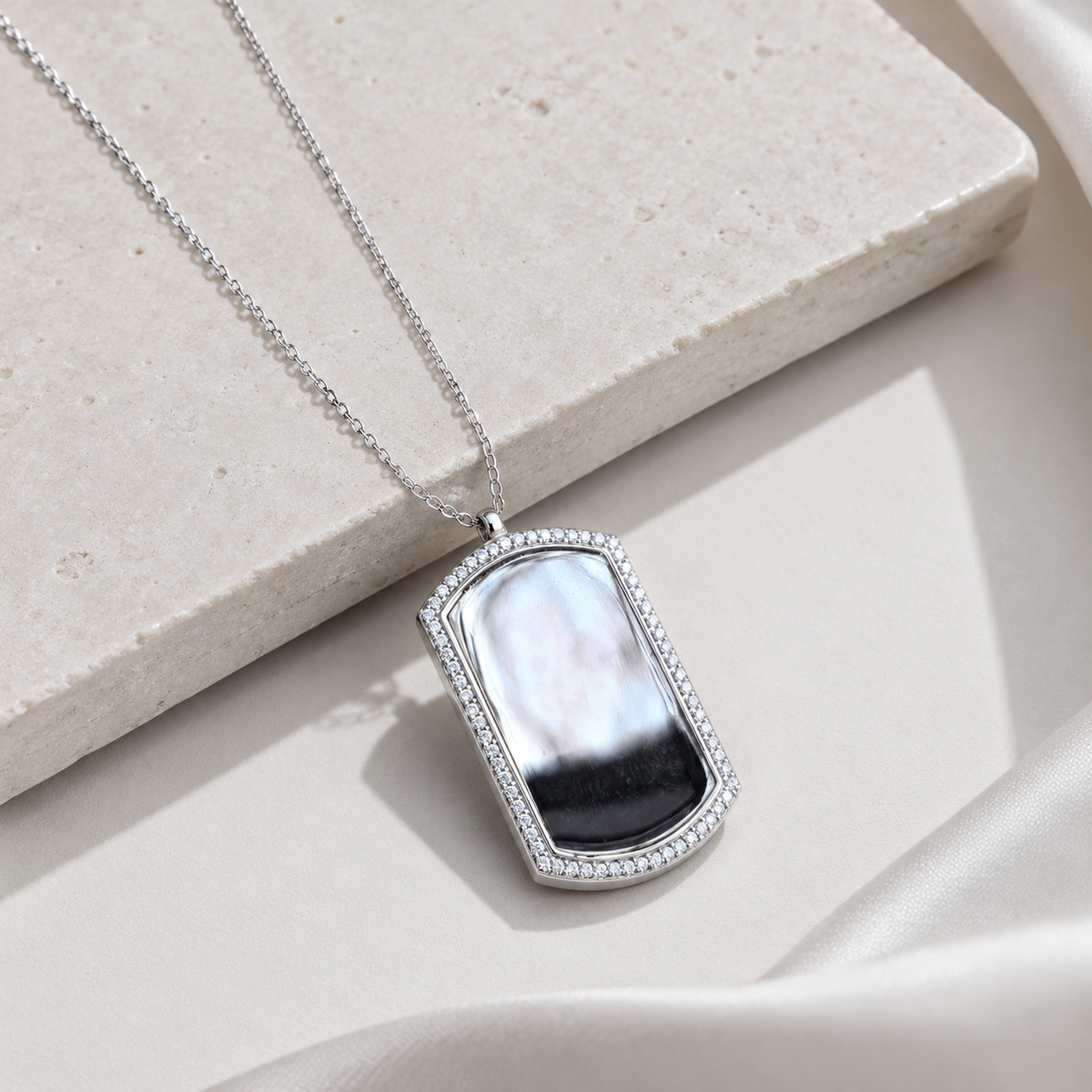 Angled view of a dog tag CZ necklace with a slim silver-tone chain.