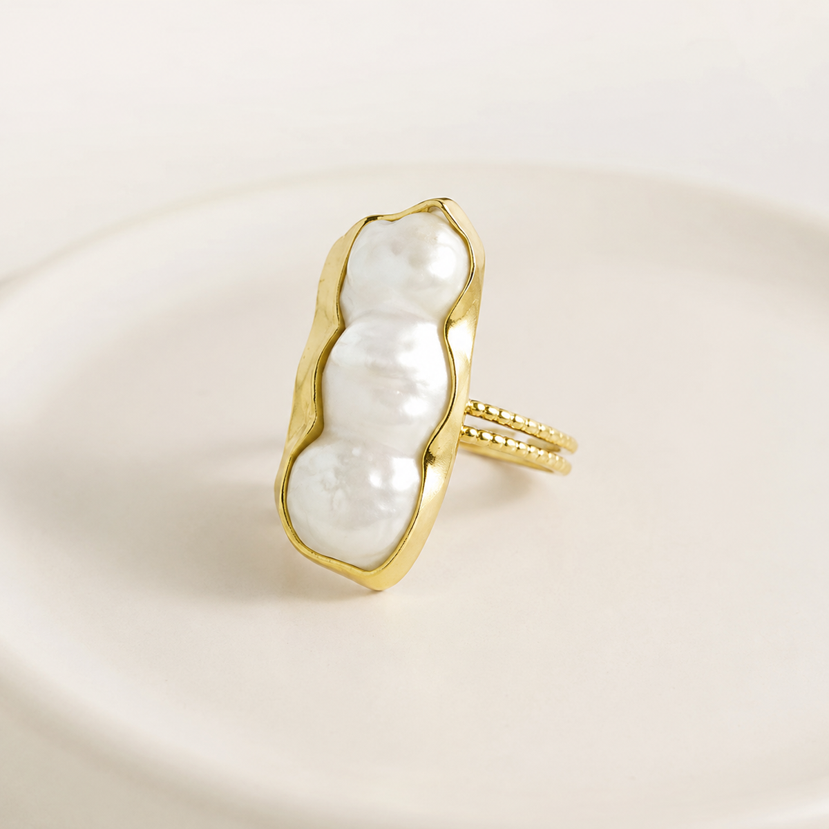 Side view of a baroque pearl statement ring with a gold-plated band.