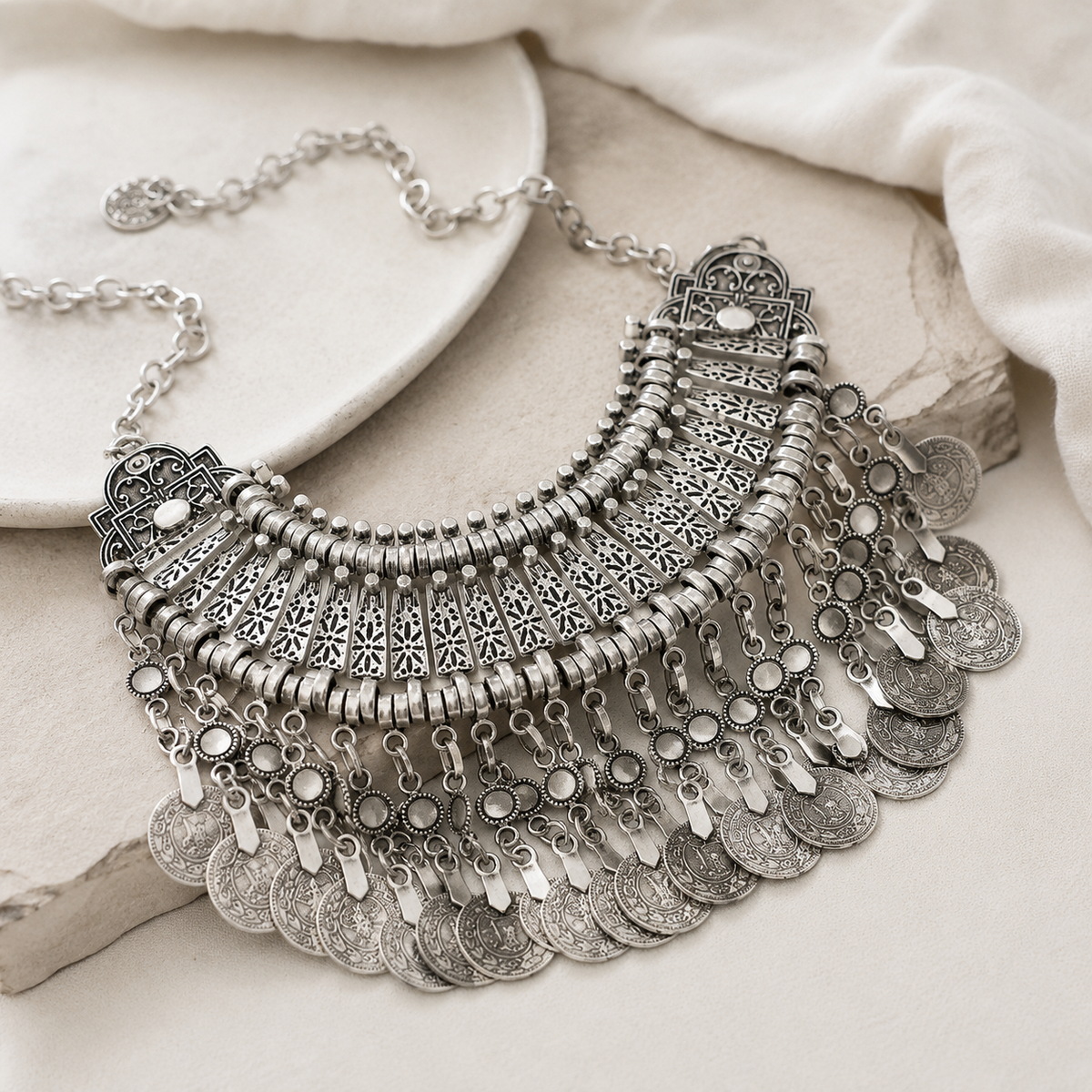 Angled view of a silver-tone bib necklace with layered fringe and detailed links.