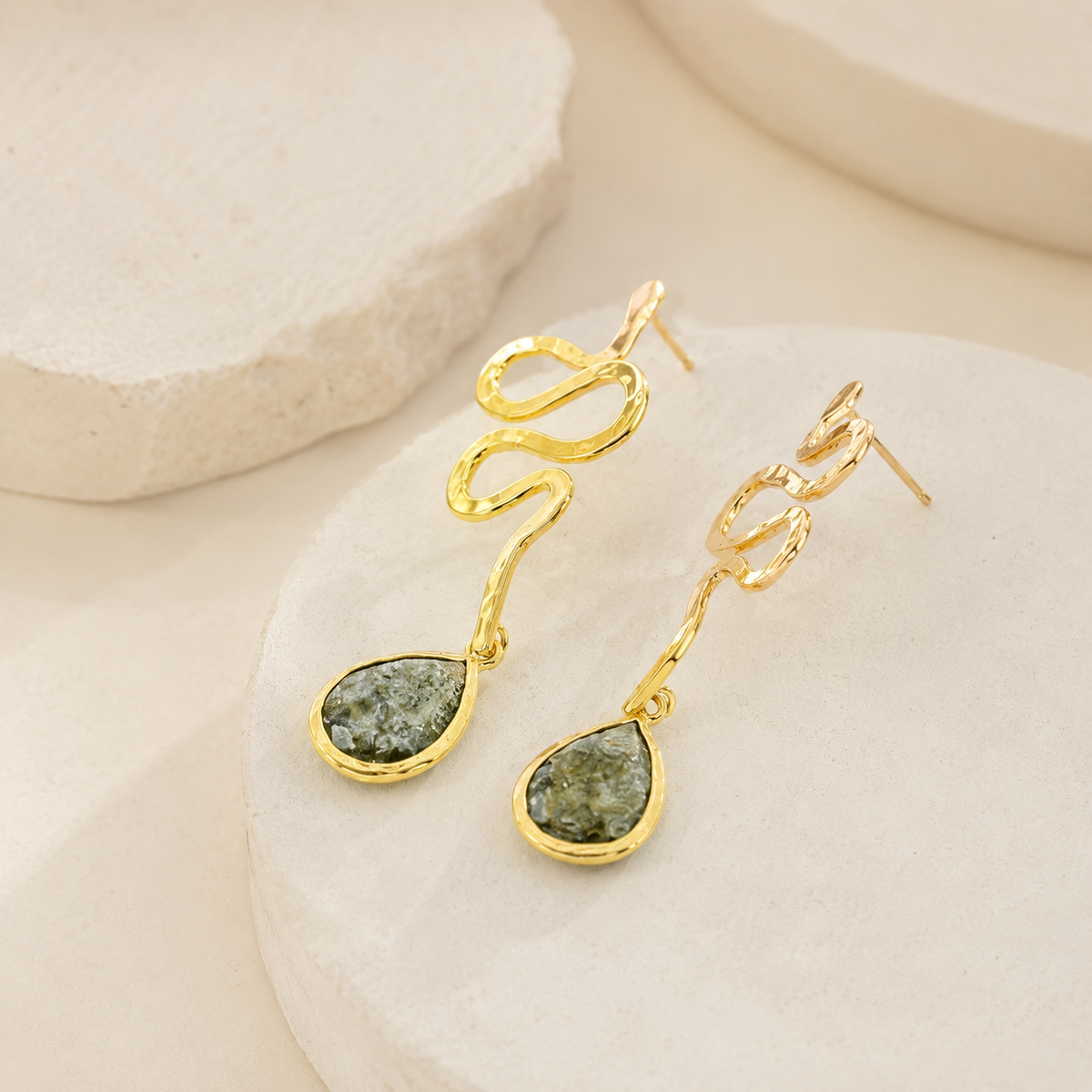 Side view of gold-plated snake drop earrings with teardrop accents.