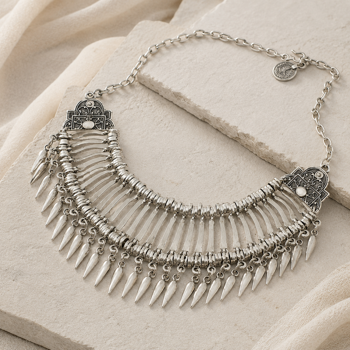 Angled view of a silver-tone fan collar necklace with teardrop dangles.