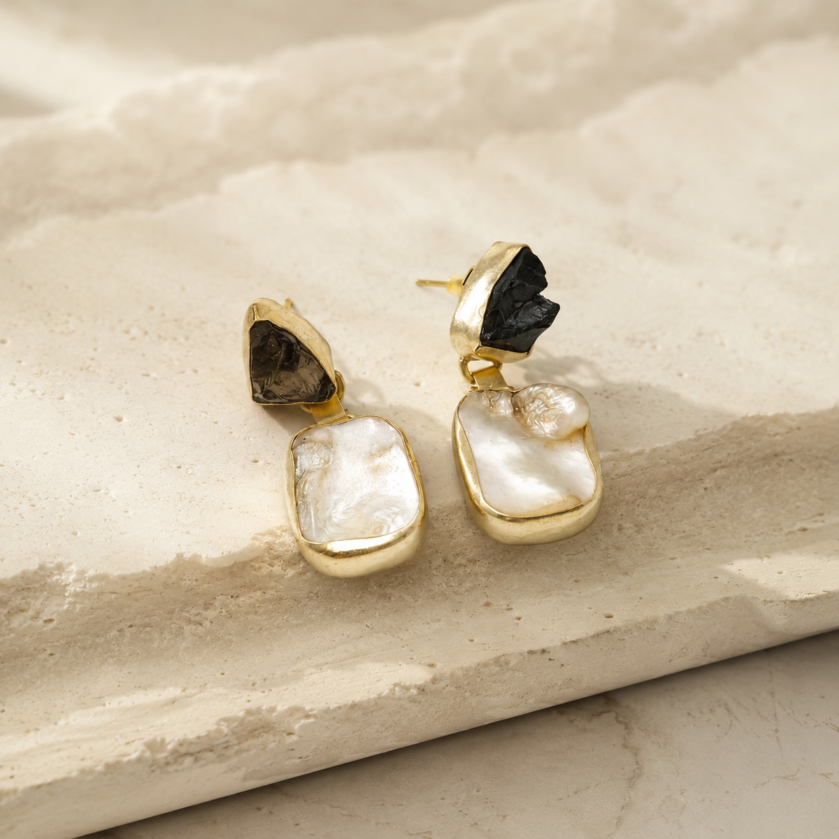 Angle view of gold-plated drop earrings with smoky quartz and mother of pearl.