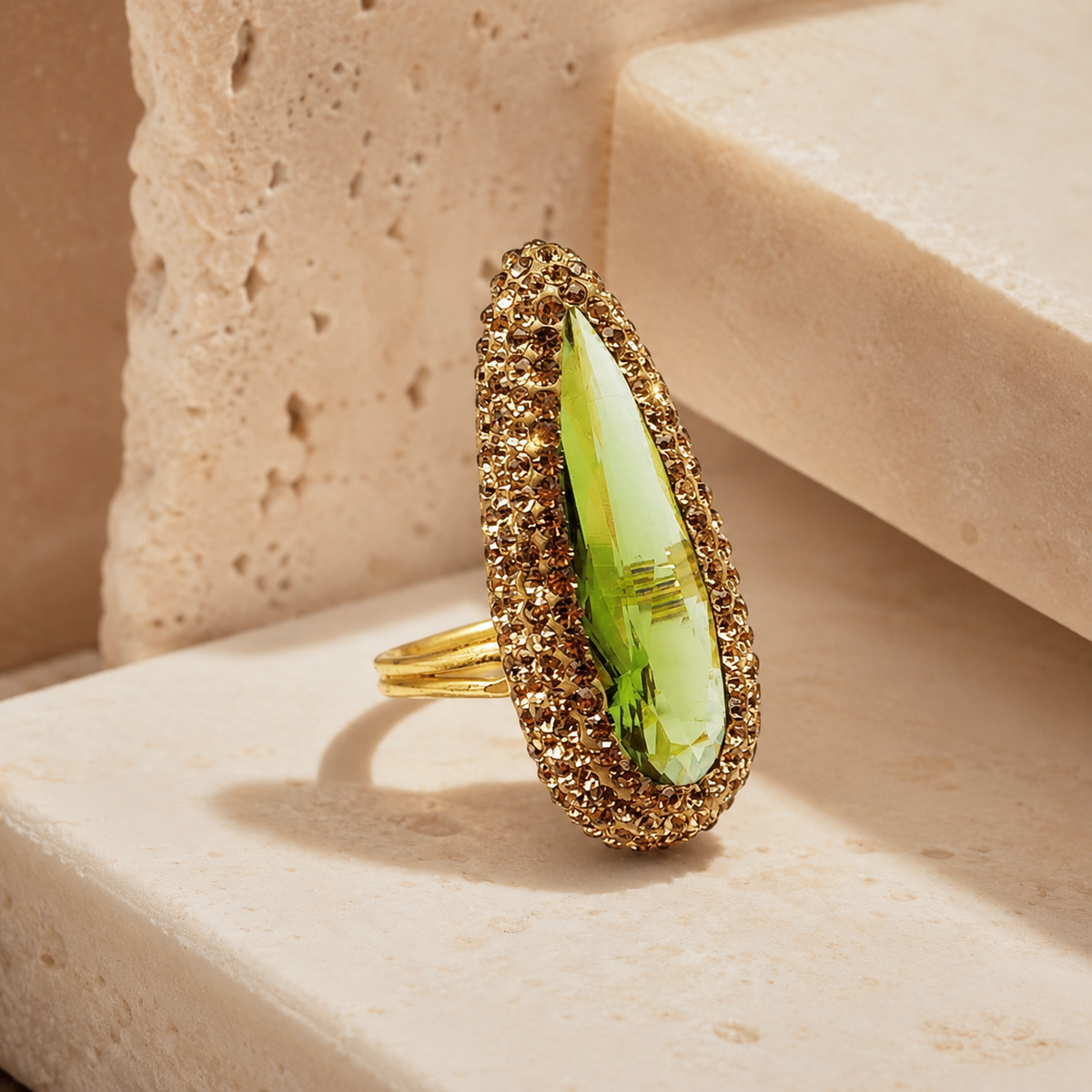 Side angle view of a gold-tone ring with a marquise-cut green center stone.