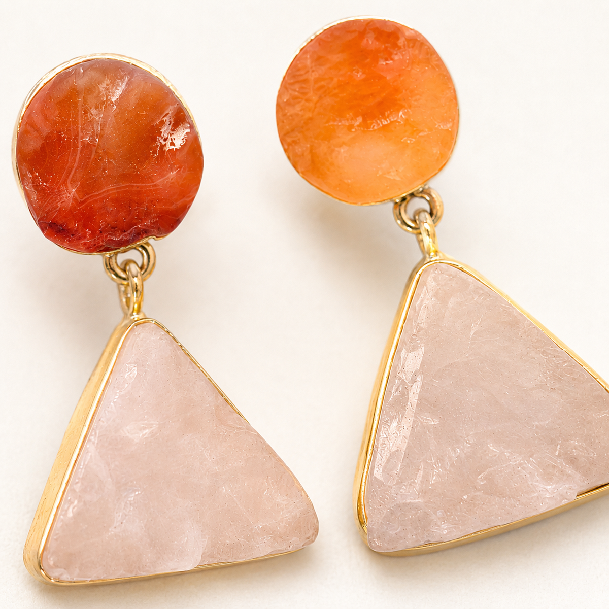 Close view of gold-plated drop earrings with textured rose quartz and carnelian stones.