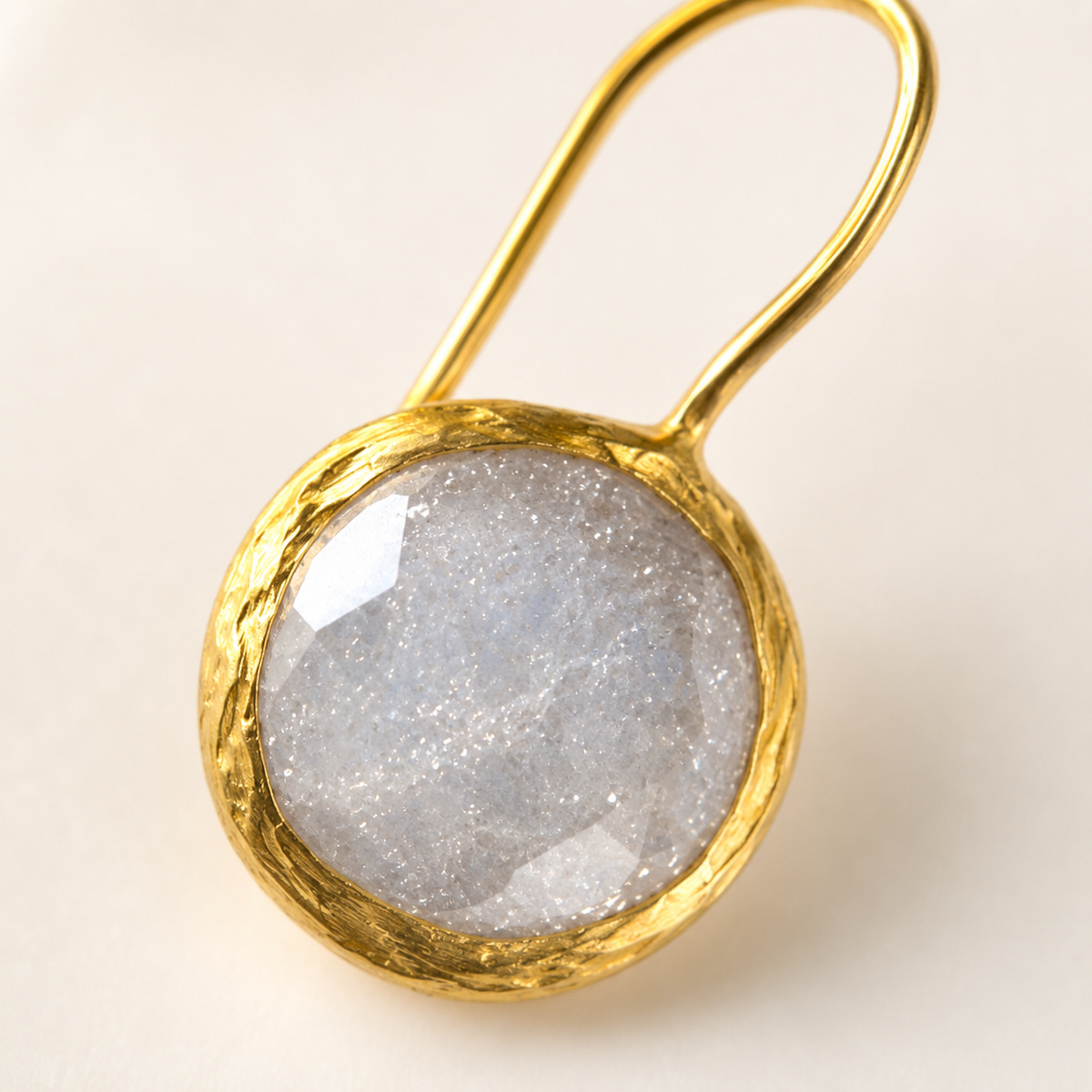 Close view of round clear CZ stones set in gold-plated earrings.