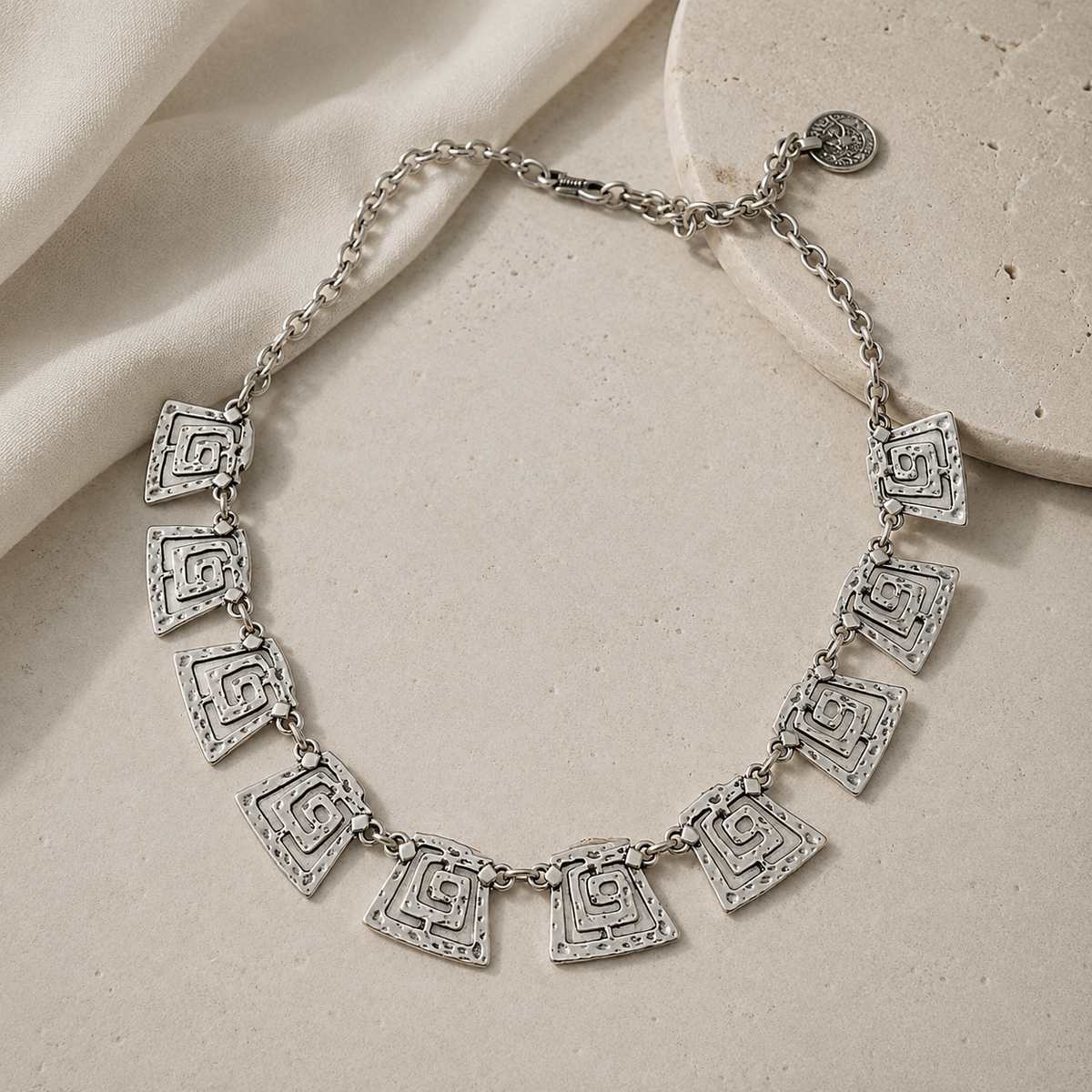 Silver-tone statement necklace with geometric spiral square links.