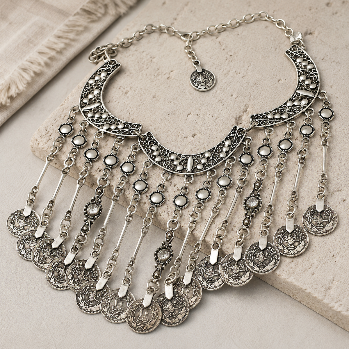 Angled view of a silver-tone crescent coin fringe statement necklace.