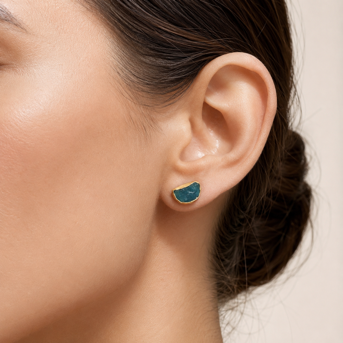 Close-up of rough apatite stud earrings with organic blue stones and gold-tone edges.