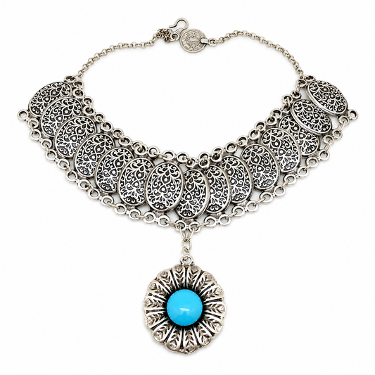 Silver-tone necklace with filigree medallions and a turquoise center pendant.