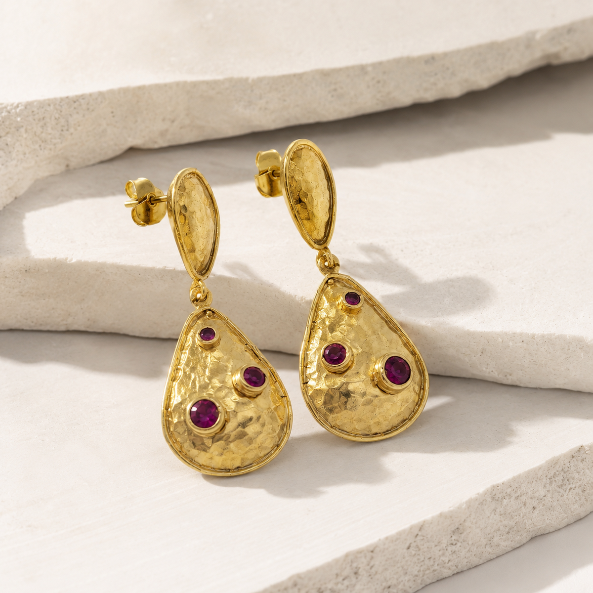 Angle view of gold-plated teardrop earrings with clear crystal accents.