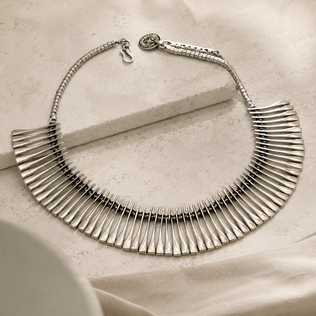 Angled view of a silver-tone ribbed fan collar necklace.