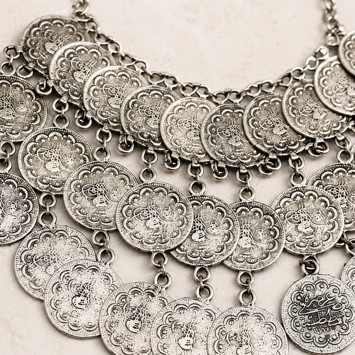 Close view of the textured coin details on the silver-tone necklace.