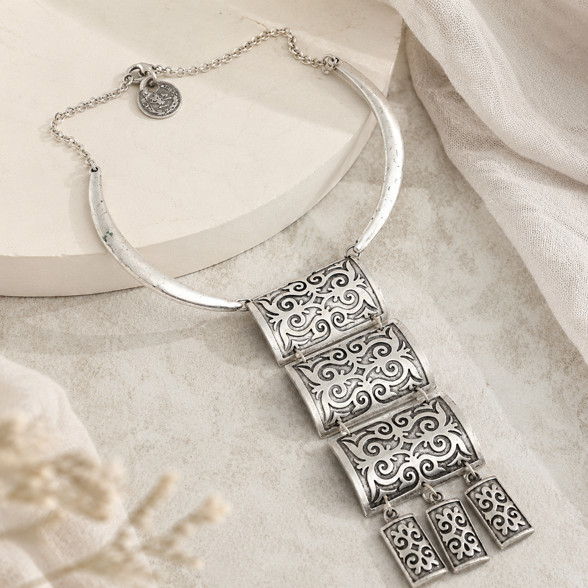 Angled view of a silver-tone necklace with black enamel-inspired panels.