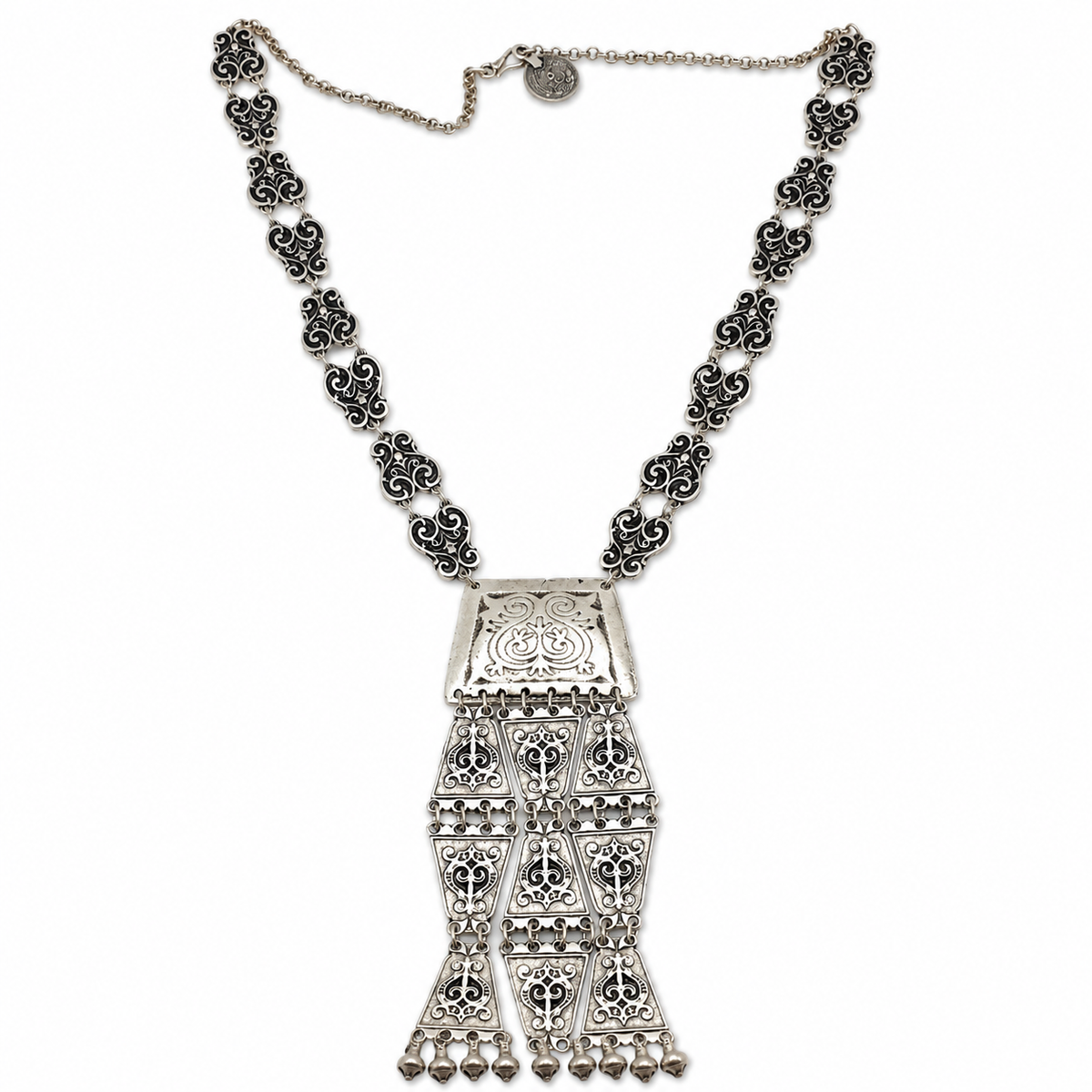 Silver-tone necklace with triangle coin links and a detailed tassel pendant.
