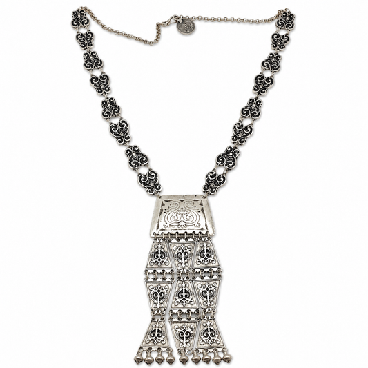 Silver-tone necklace with triangle coin links and a detailed tassel pendant.
