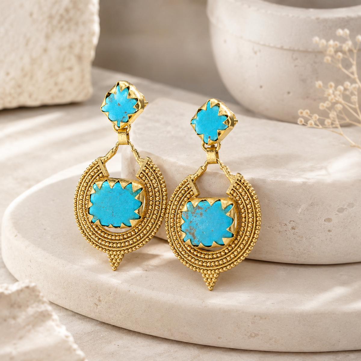 Angle view of gold-plated drop earrings with turquoise square stones.