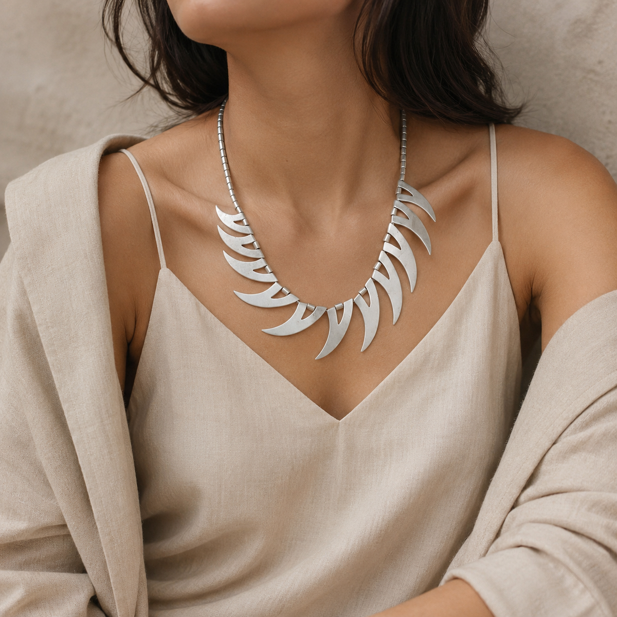 Silver-tone collar necklace with a sculptural crescent design.