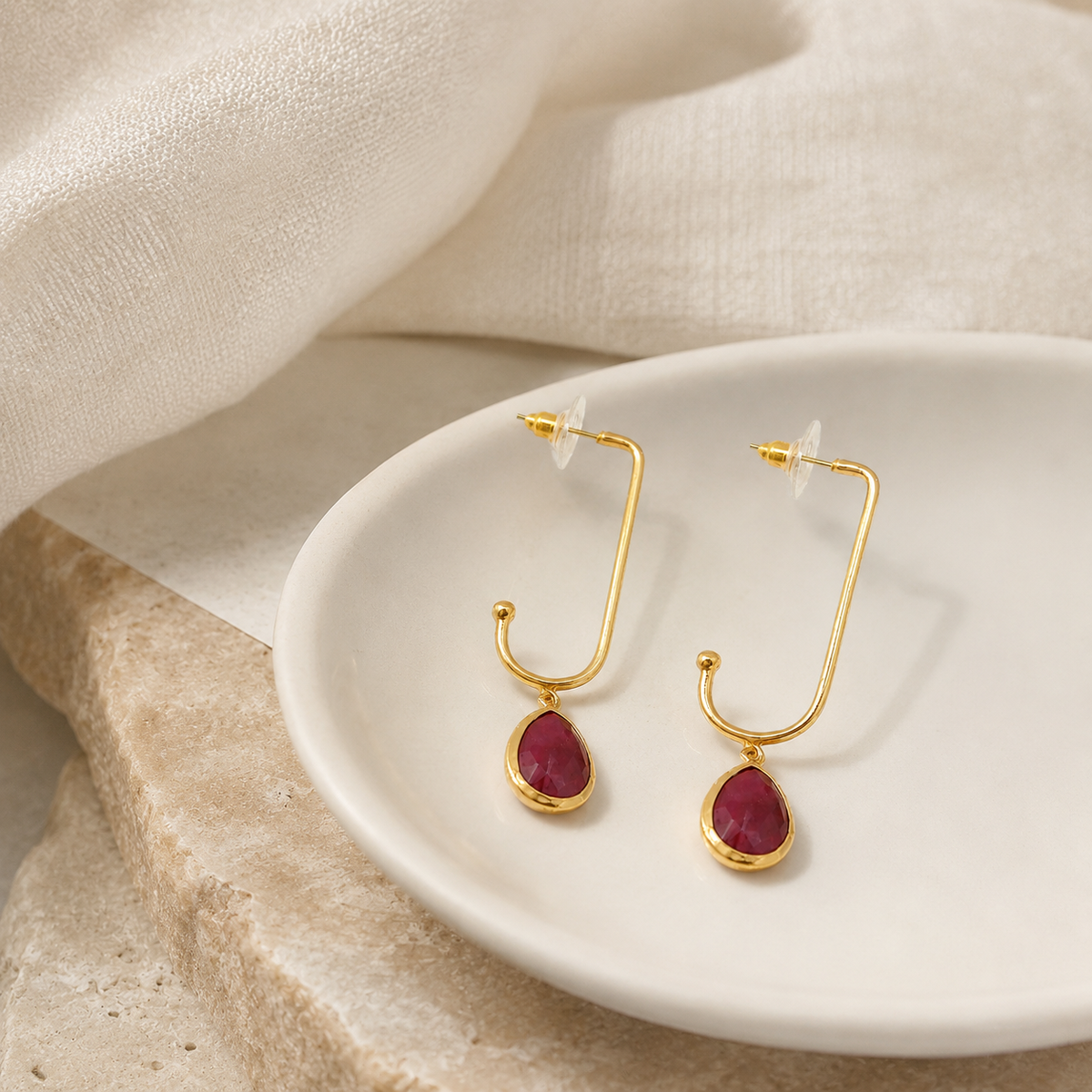 Gold-plated open drop earrings with green stone accents.