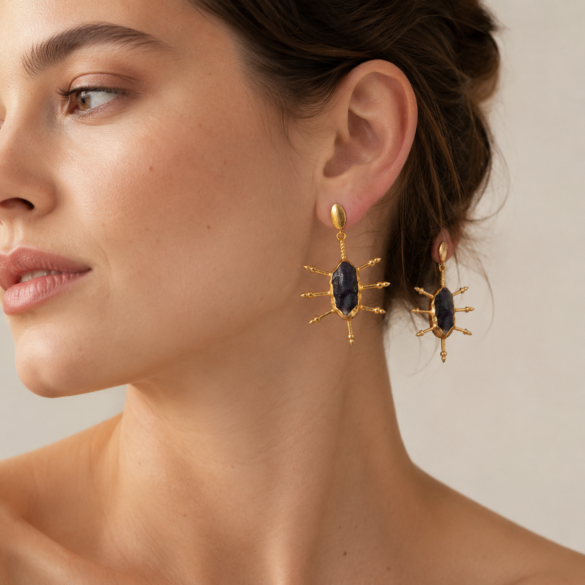 Pair of raw amethyst earrings with gold-plated details on a white background.