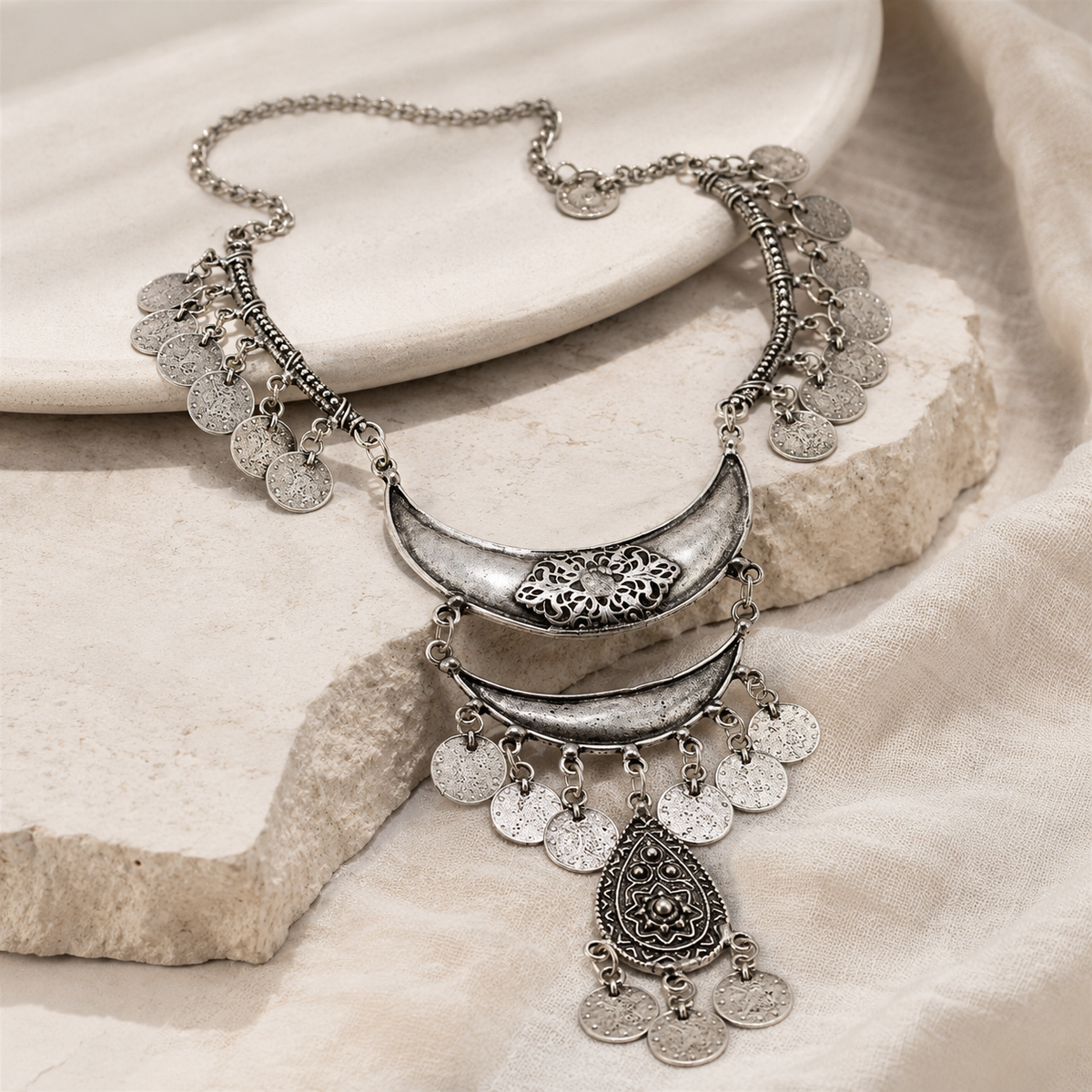 Angled view of a silver-tone bib necklace with textured coin charms.