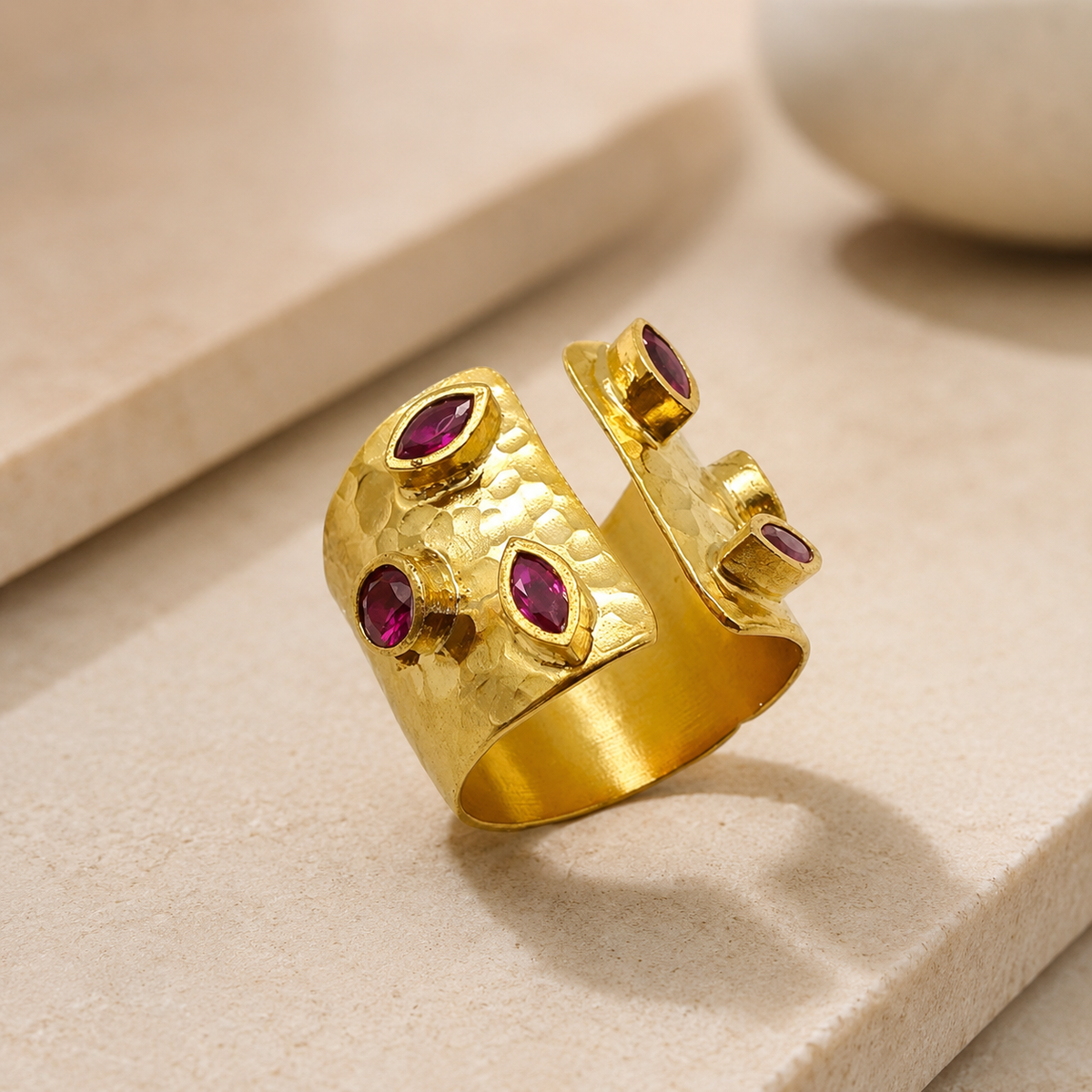 Angled view of a gold-plated open cuff ring with cherry-toned CZ accents.