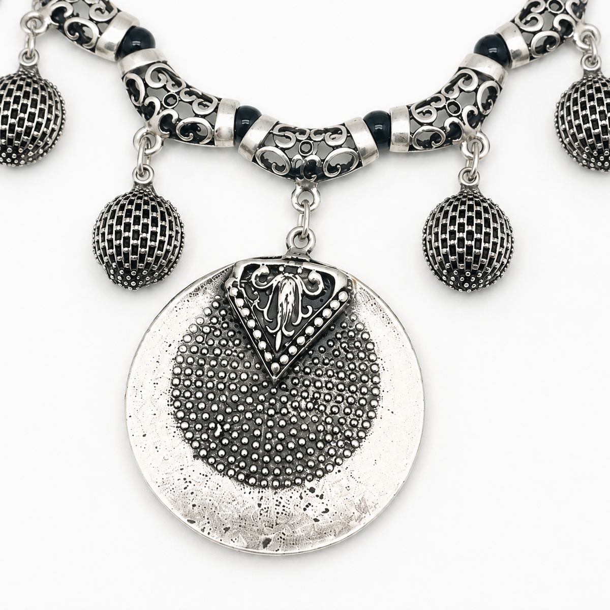 Close view of the necklace’s textured silver-toned medallion and bead details.
