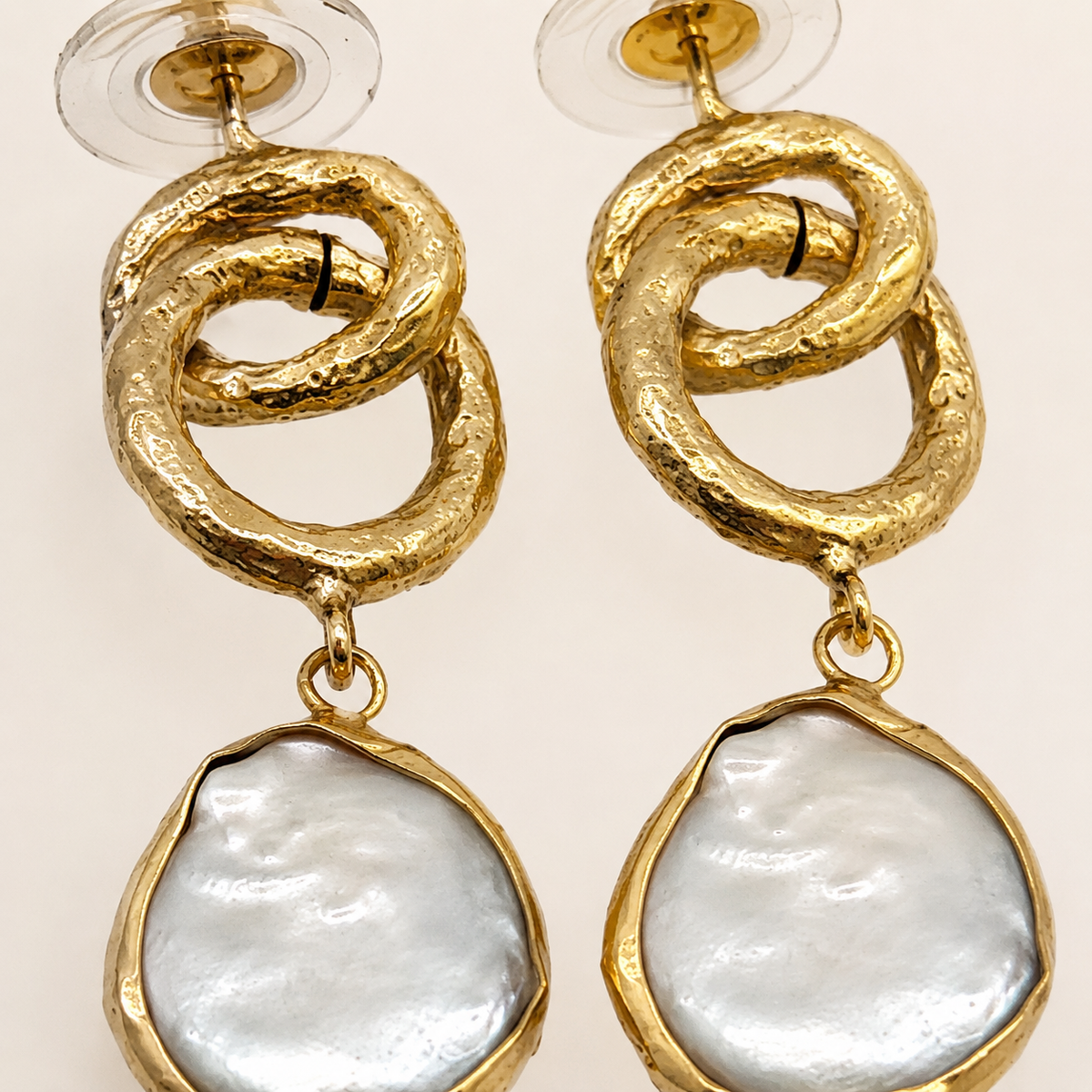 Close view of textured gold links and pearl-inspired drops.
