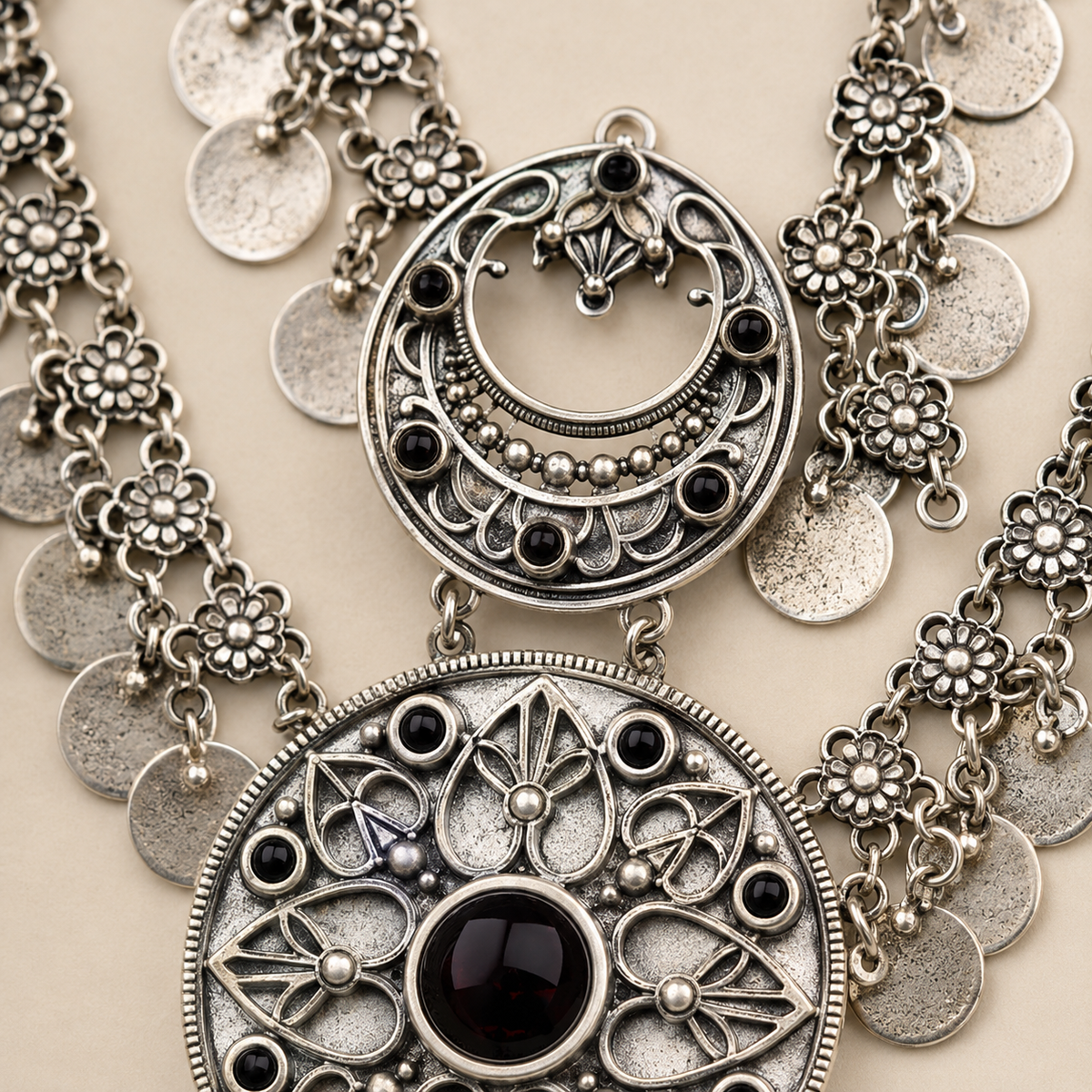 Close view of the necklace's textured coin fringe and red center stone.