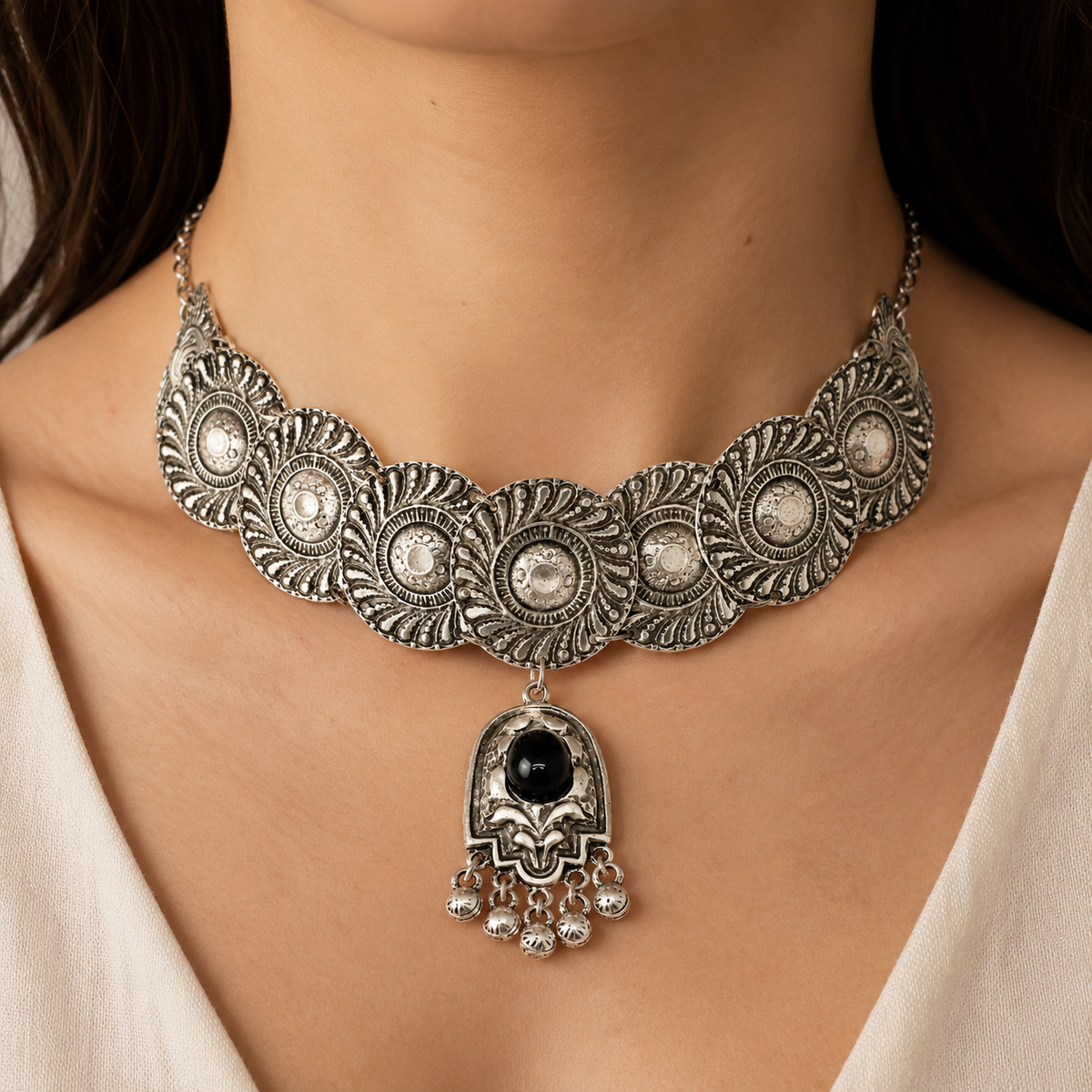 Silver-tone choker necklace with detailed embossed discs and a black stone centerpiece.