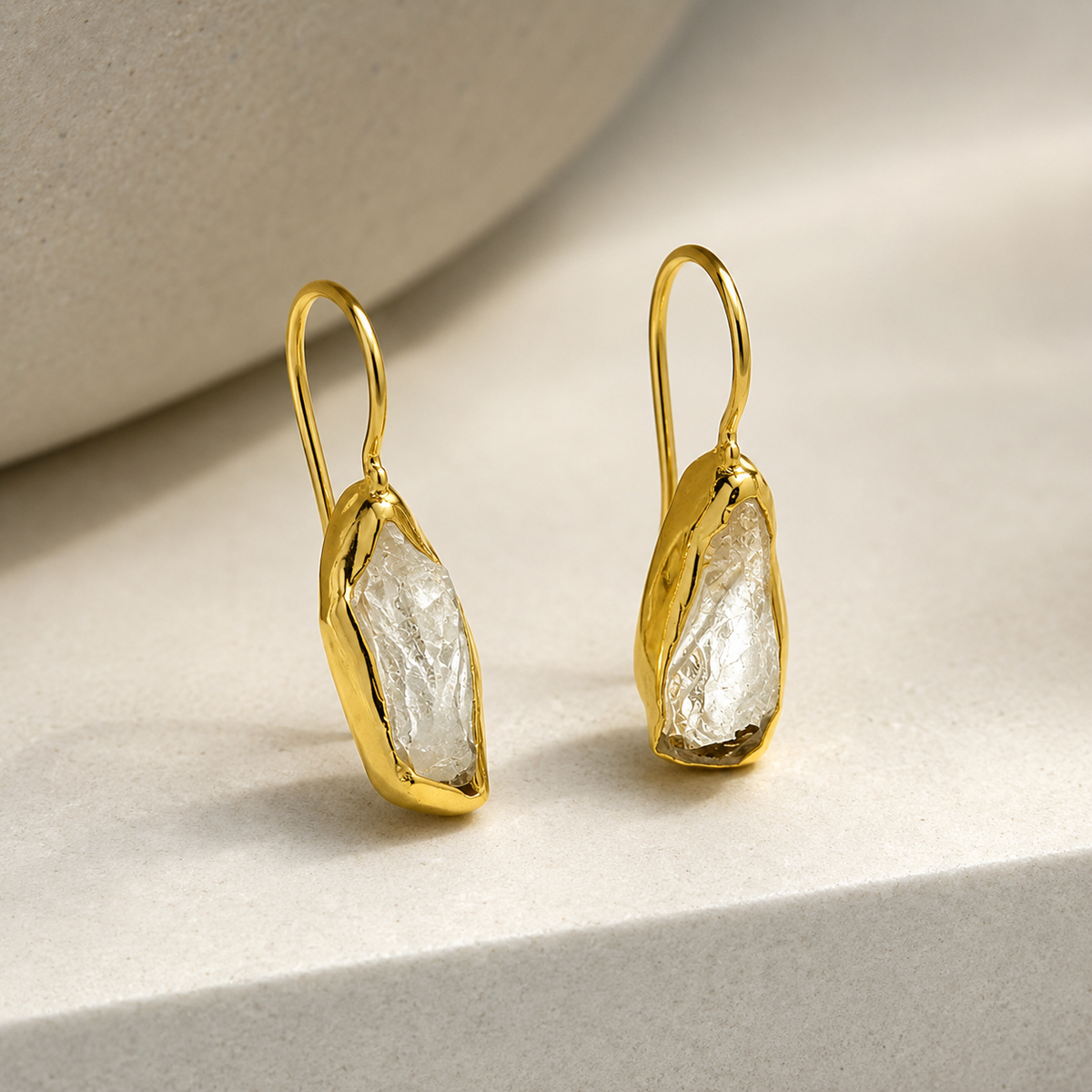 Side angle view of clear quartz drop earrings with gold-plated hooks.