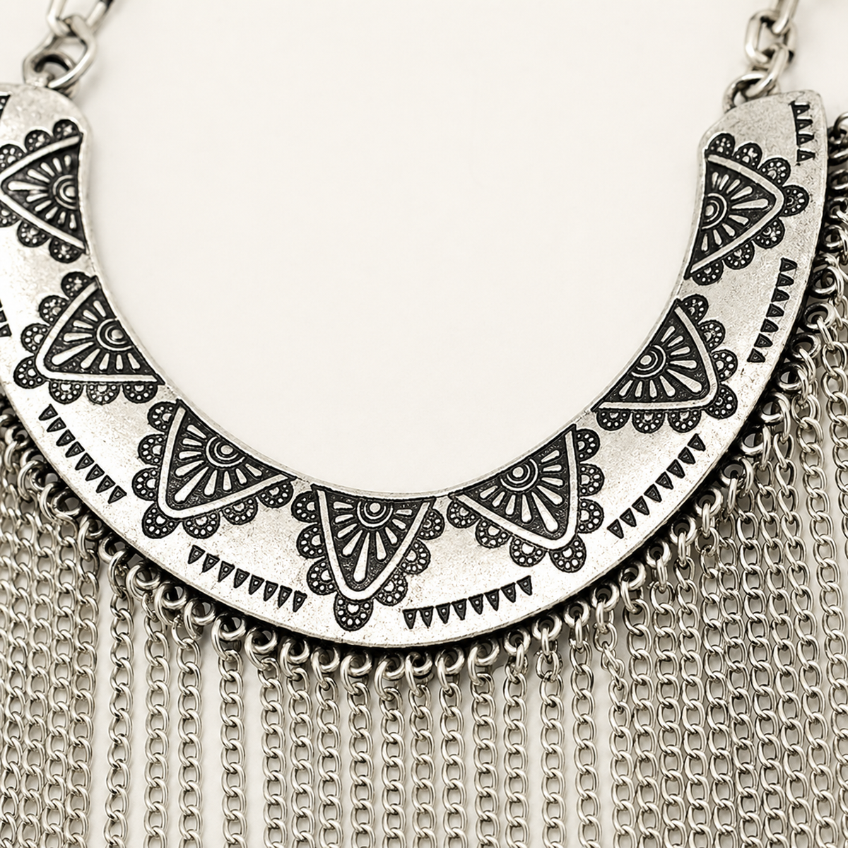 Close view of the engraved silver-tone collar and textured chain fringe.