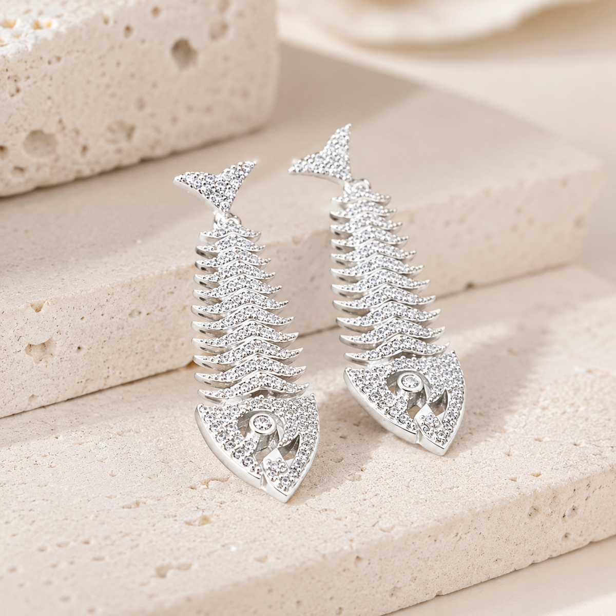 Angled view of silver fish bone earrings with sparkling CZ accents.